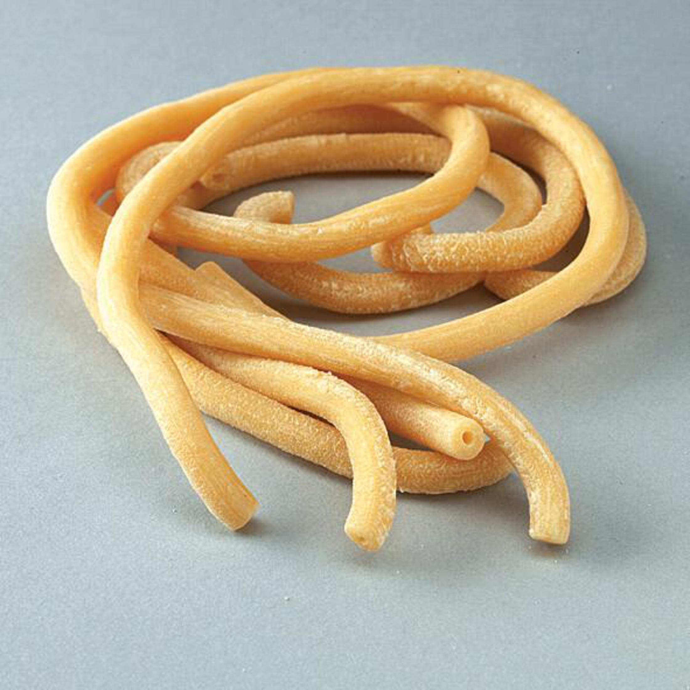 Pâtes jaunes bouclées disposées sur une surface grise, accent sur la texture.