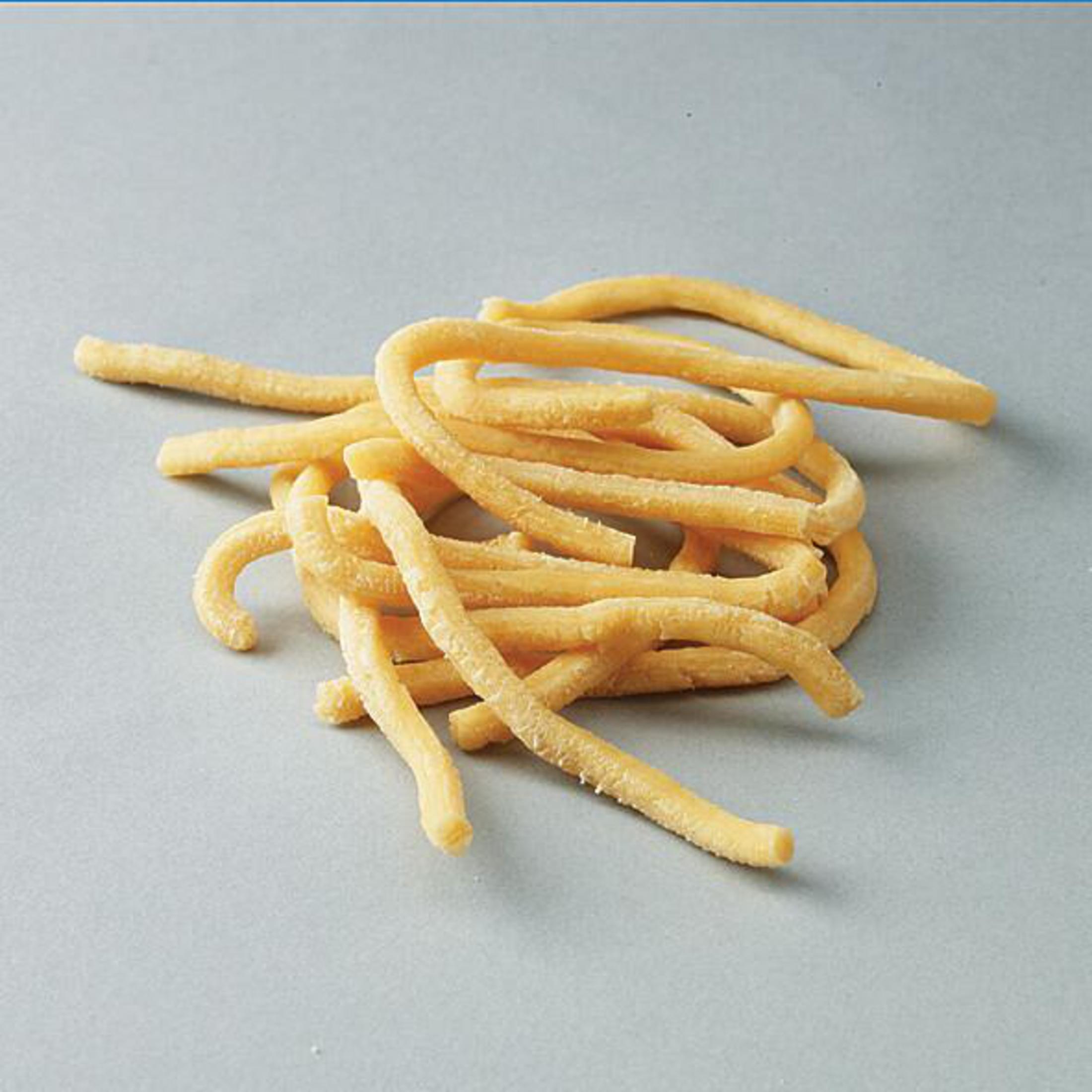 Gelbe Cavatappi-Nudeln auf hellgrauer Oberfläche.