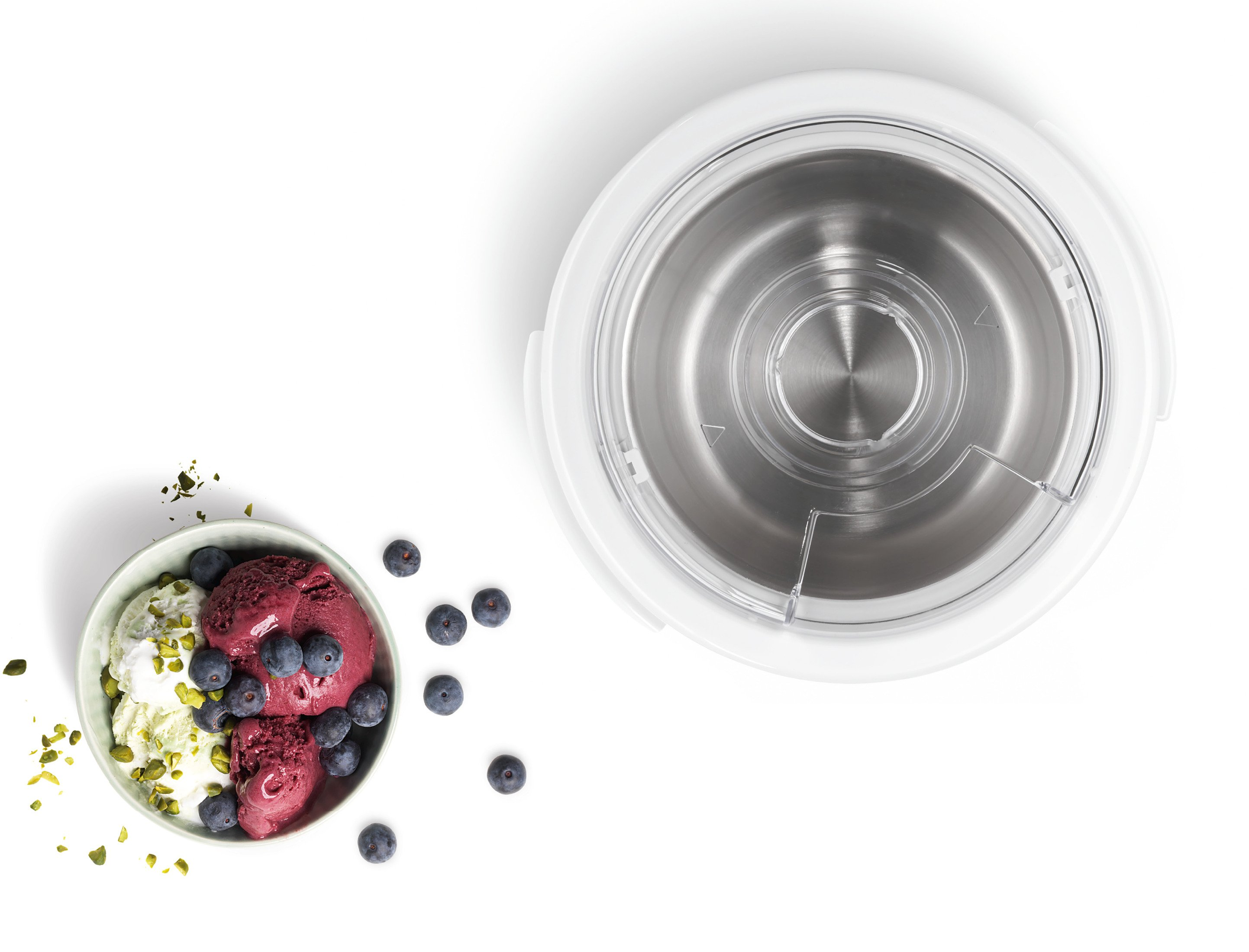 Eis, Blaubeeren und Pistazien in einer Schüssel. Eismaschine rechts.