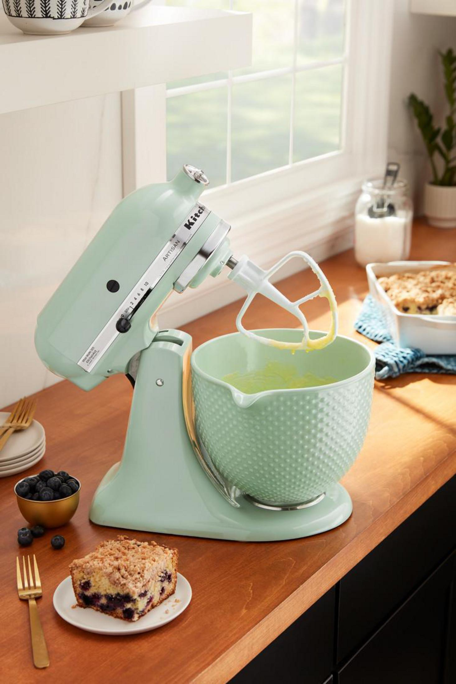 Minzgrüner KitchenAid-Mixer mit Schüssel und Zutaten auf Holzoberfläche.