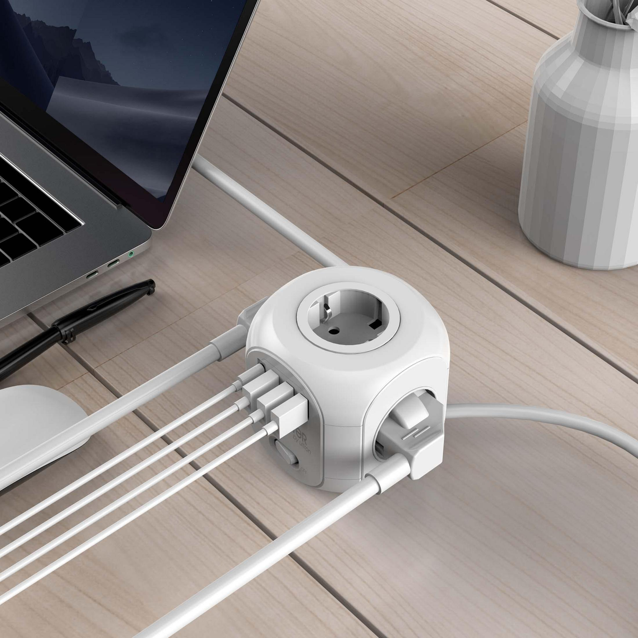 Un cubo di alimentazione bianco con prese multiple e porte USB è su una scrivania di legno con un laptop.