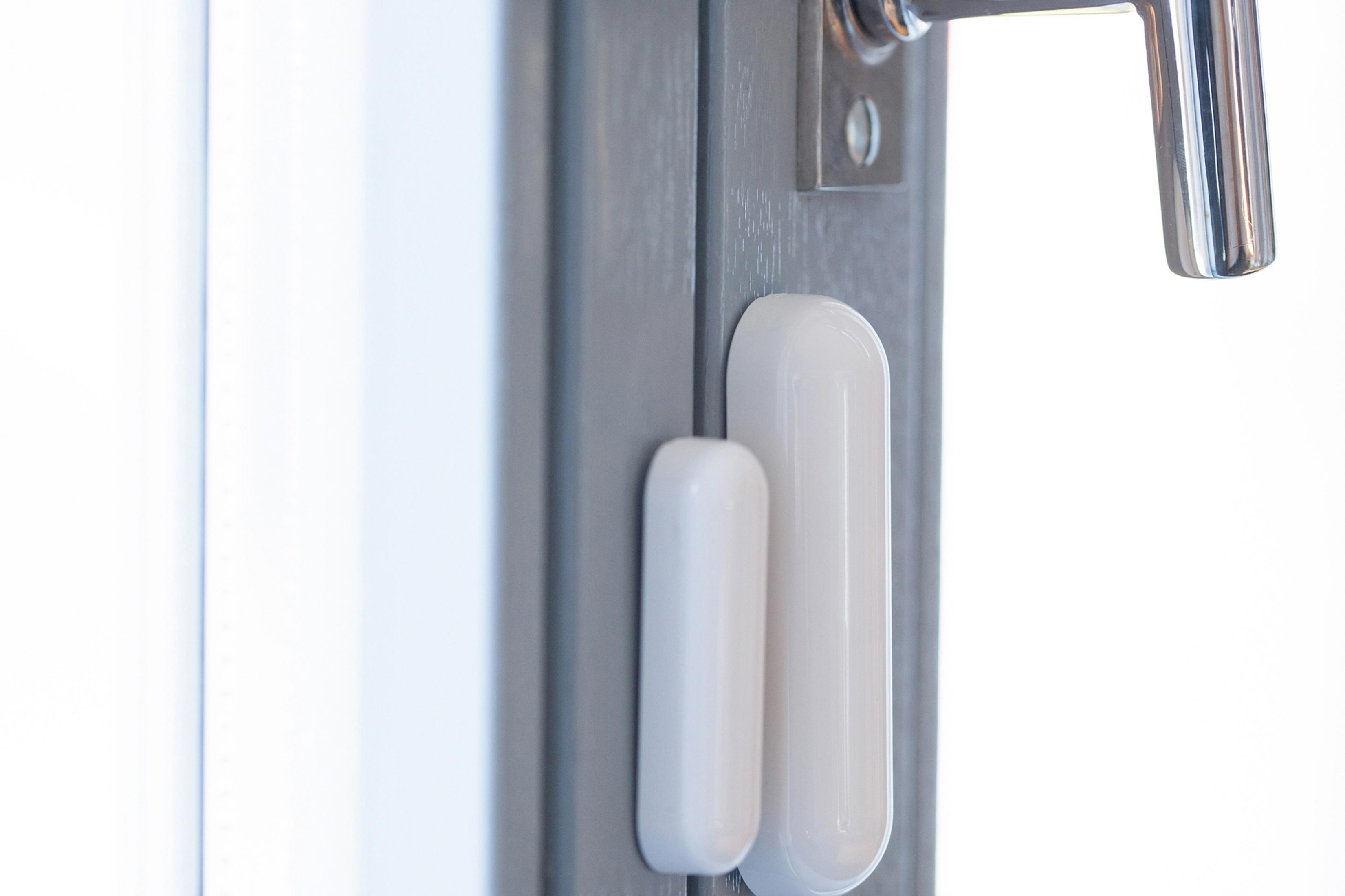 Un marco de puerta con un sensor de seguridad blanco adjunto.