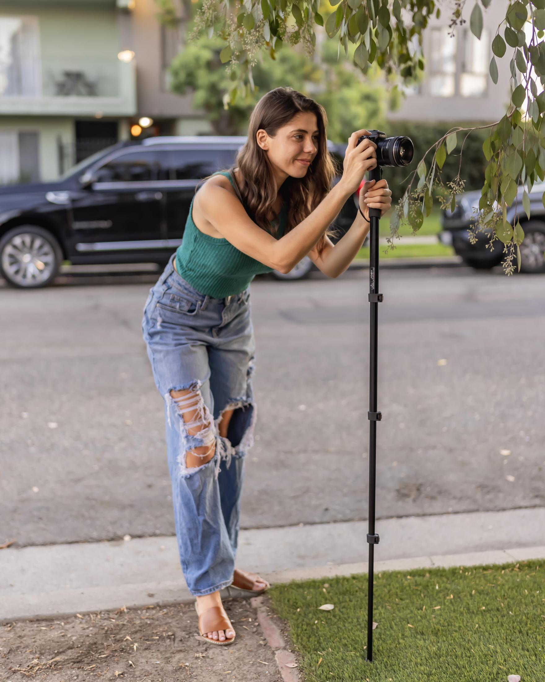 Woman taking a photo with a camera on a tripod, outdoors.