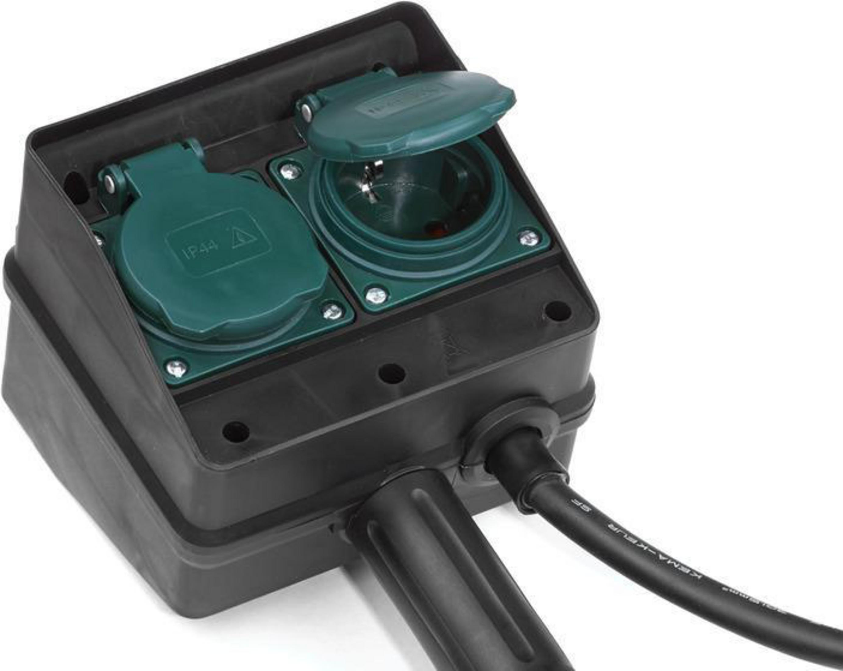 İki yeşil soketli ve siyah kablolu bir elektrik kutusu. Kutu beyaz bir yüzeyde duruyor.
