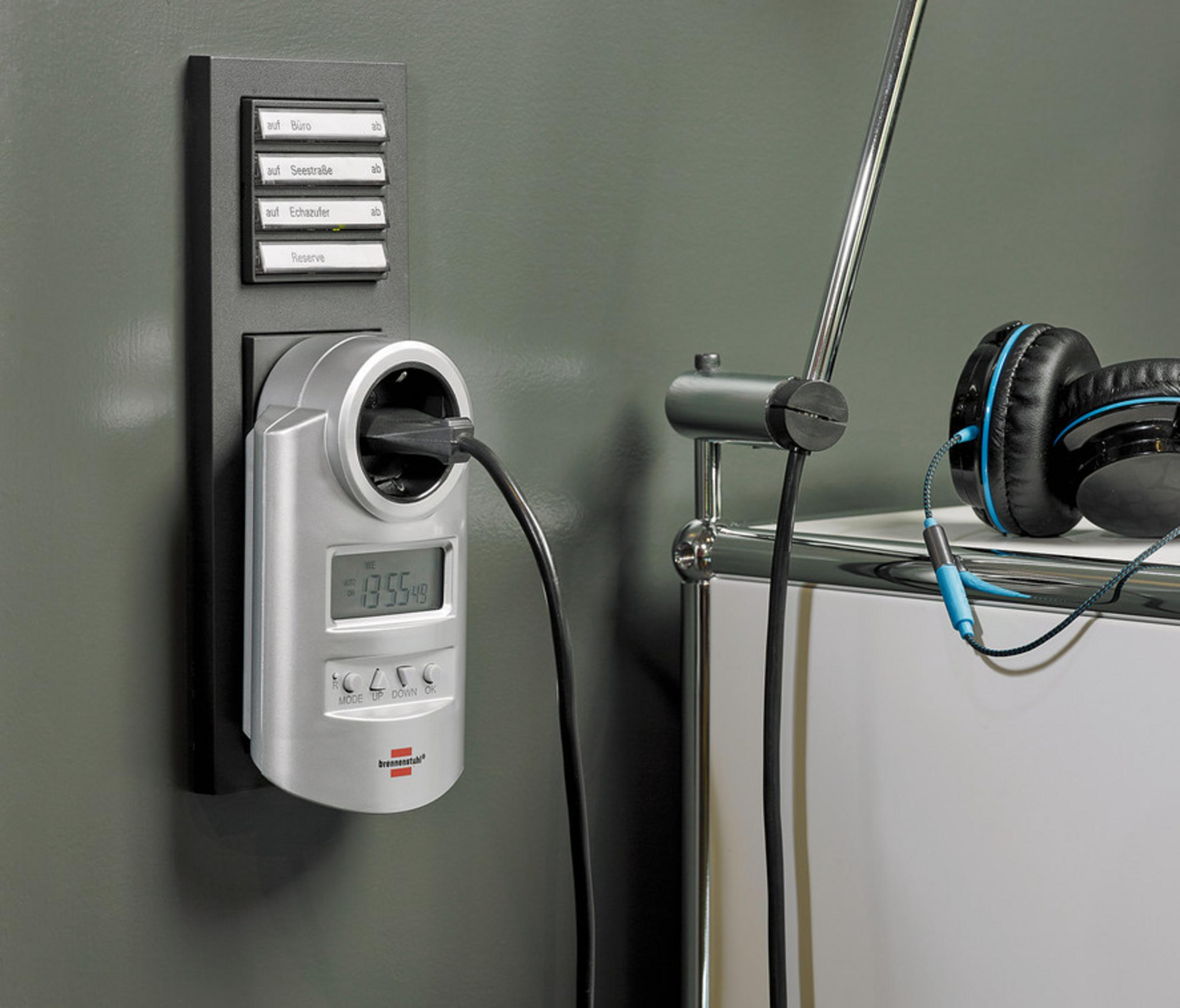 Duvara monte edilmiş, ekranlı, takılı bir elektronik cihaz. Kulaklıklar sağda.