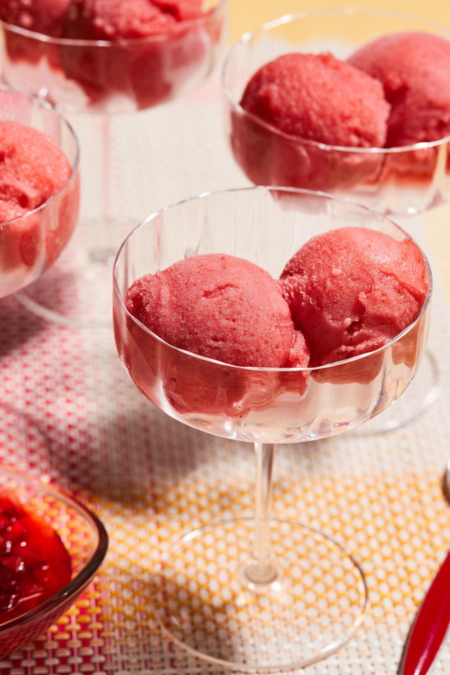 Sorbet in Gläsern, mit zwei Kugeln in jedem Glas, auf einem bunten Tisch.