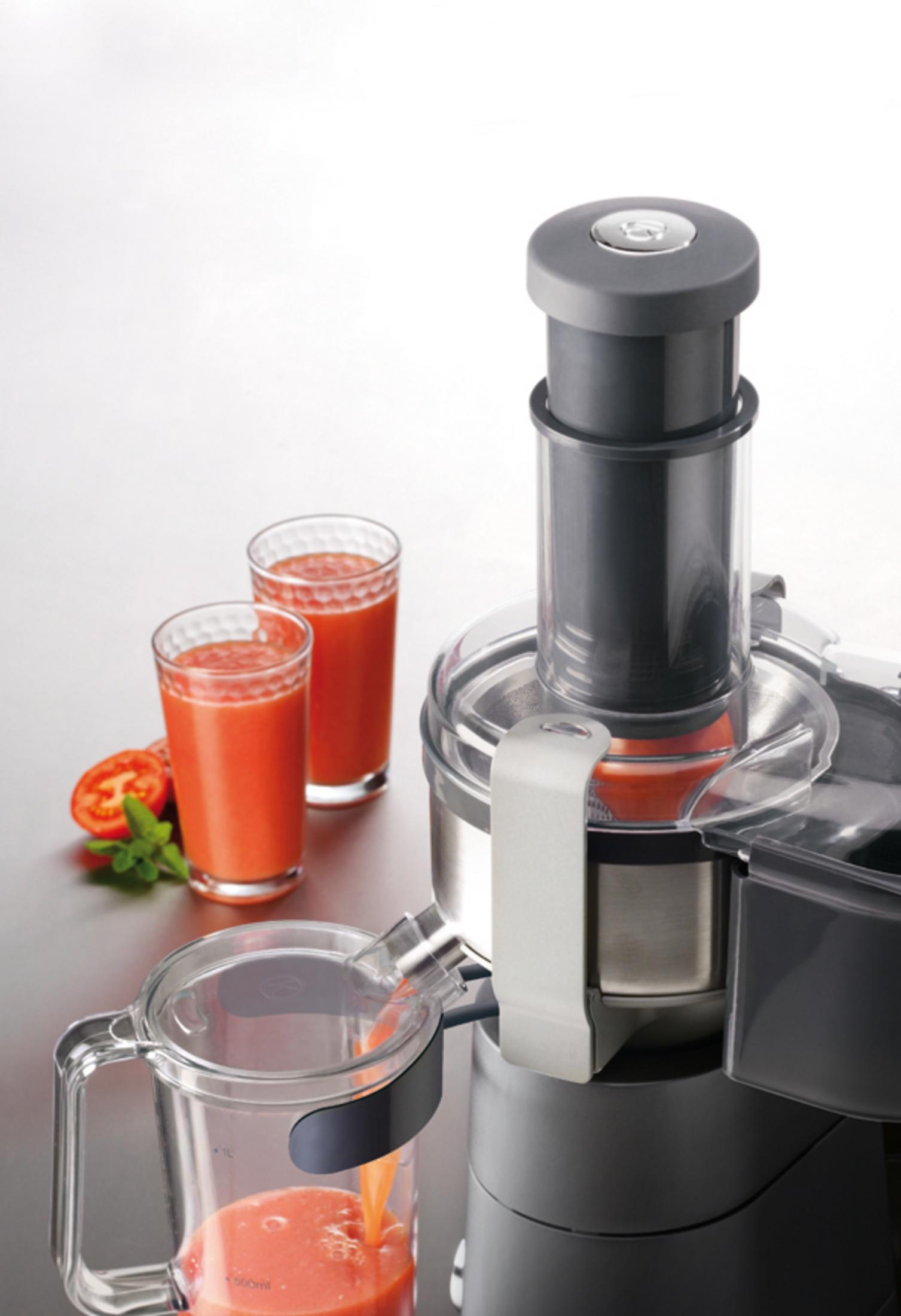 Ein Entsafter im Einsatz, mit zwei Gläsern Saft und einer Tomatenscheibe.