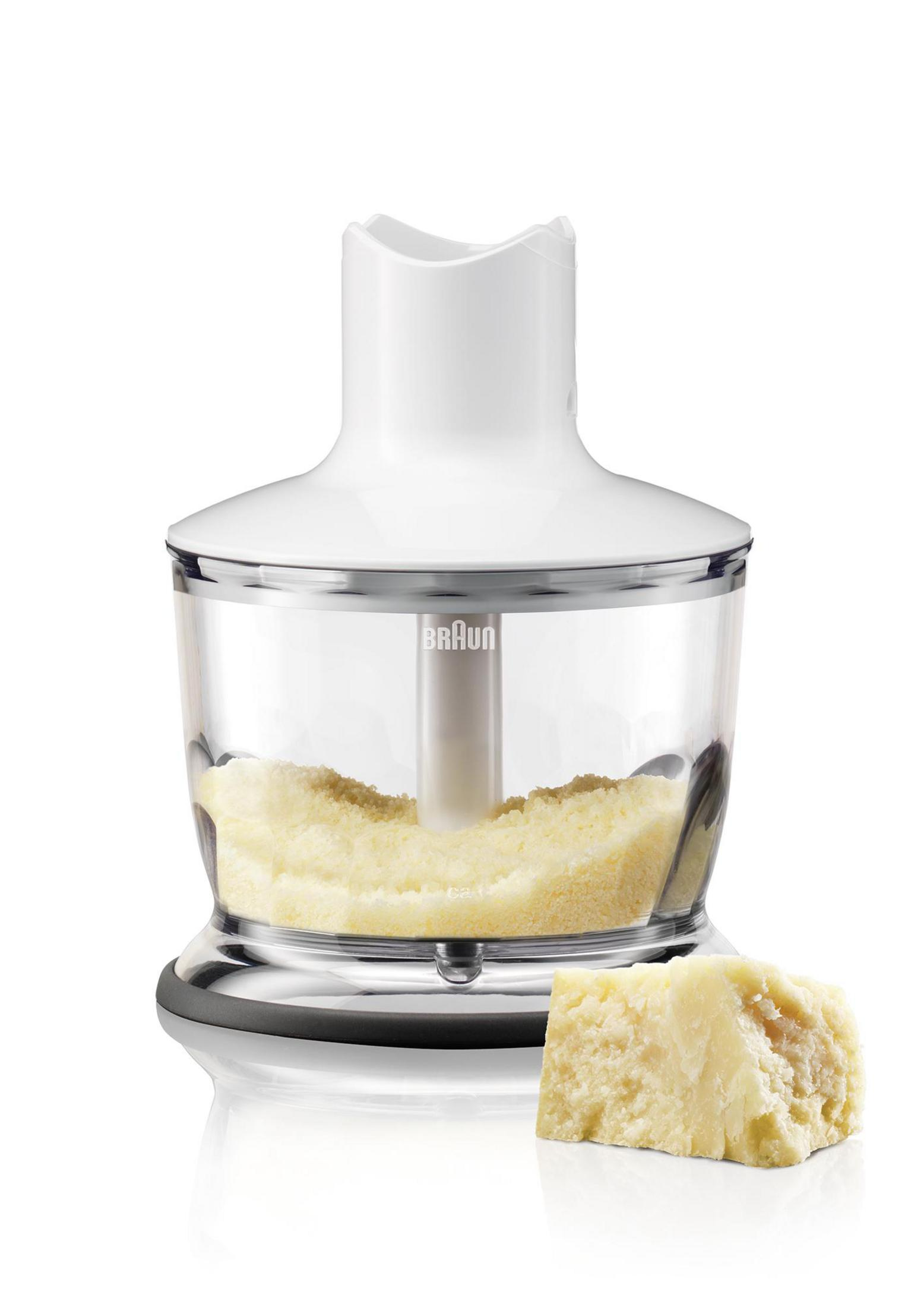 Batidora de mano Braun blanca con un recipiente transparente que contiene queso rallado y un bloque de queso.