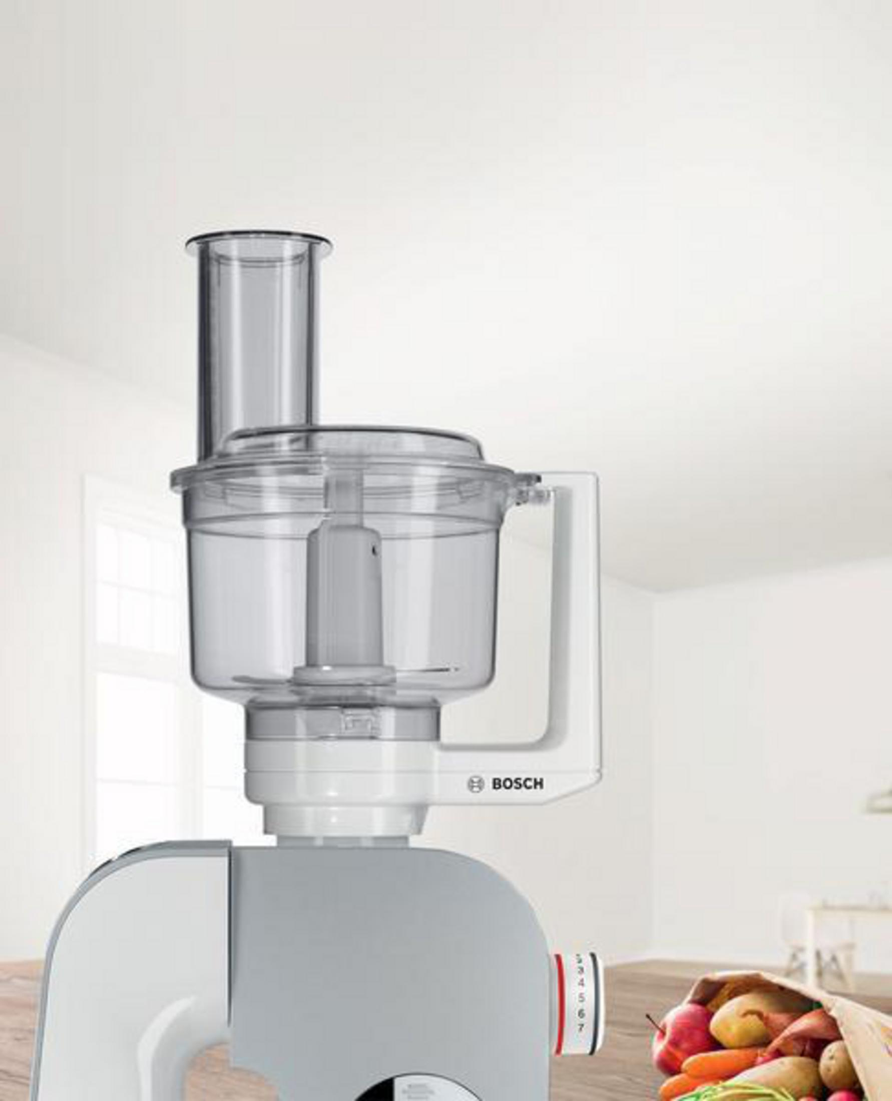 Ein Food Processor mit transparentem Behälter und weißem Griff steht auf Weiß.
