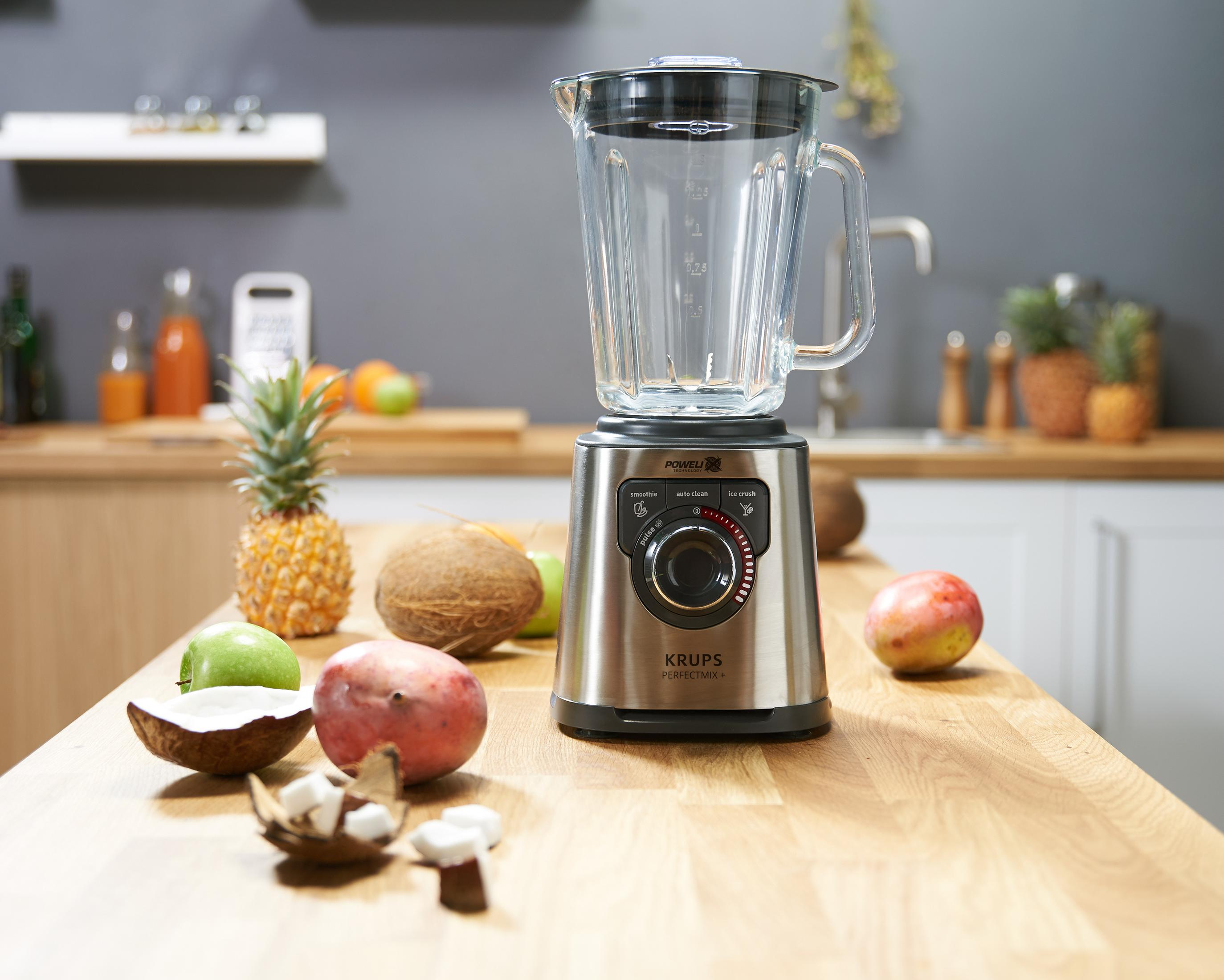 Ein silberner Mixer mit Obst auf einer Holzküchenarbeitsplatte.