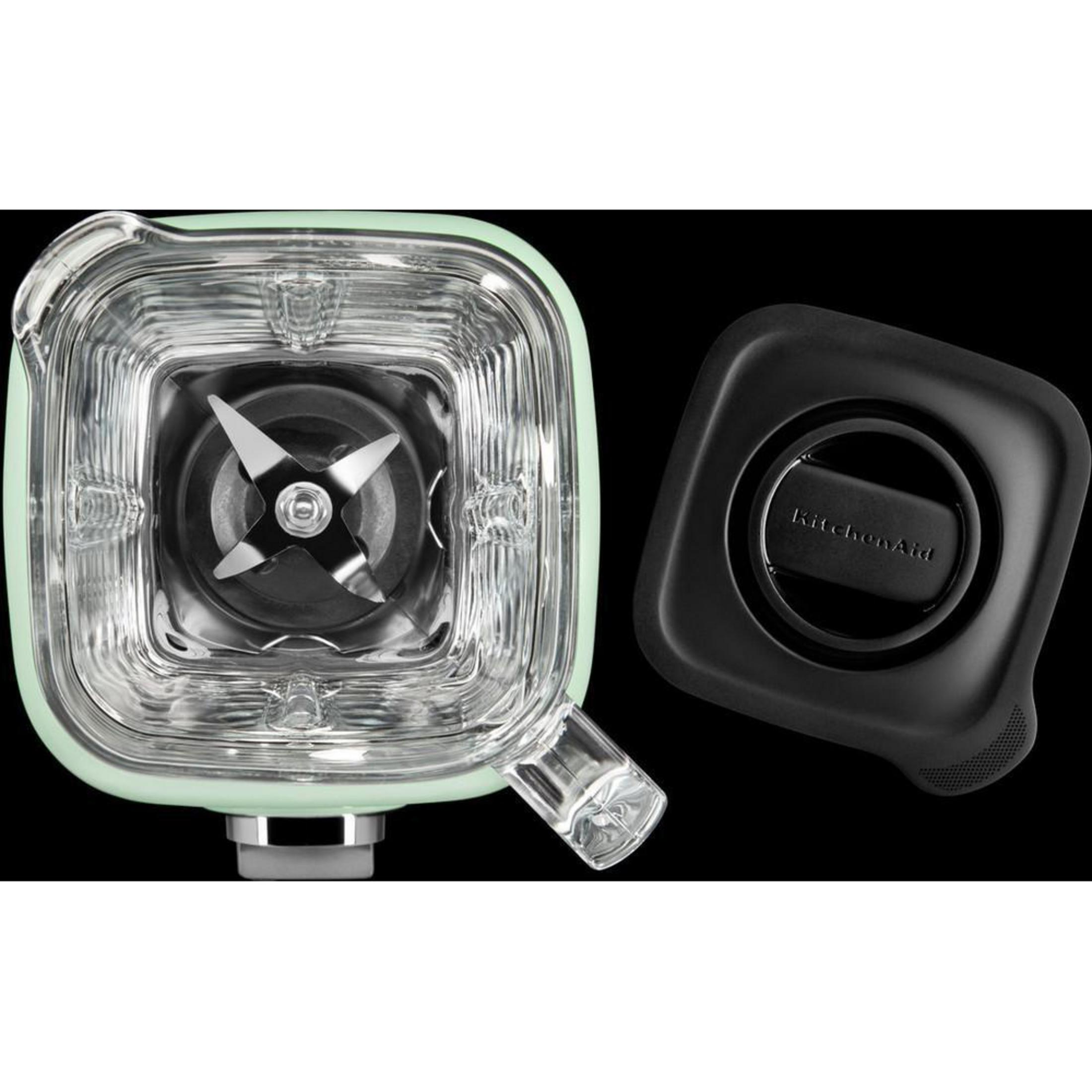 Blender jar with blades, black lid, mint green base, black background.