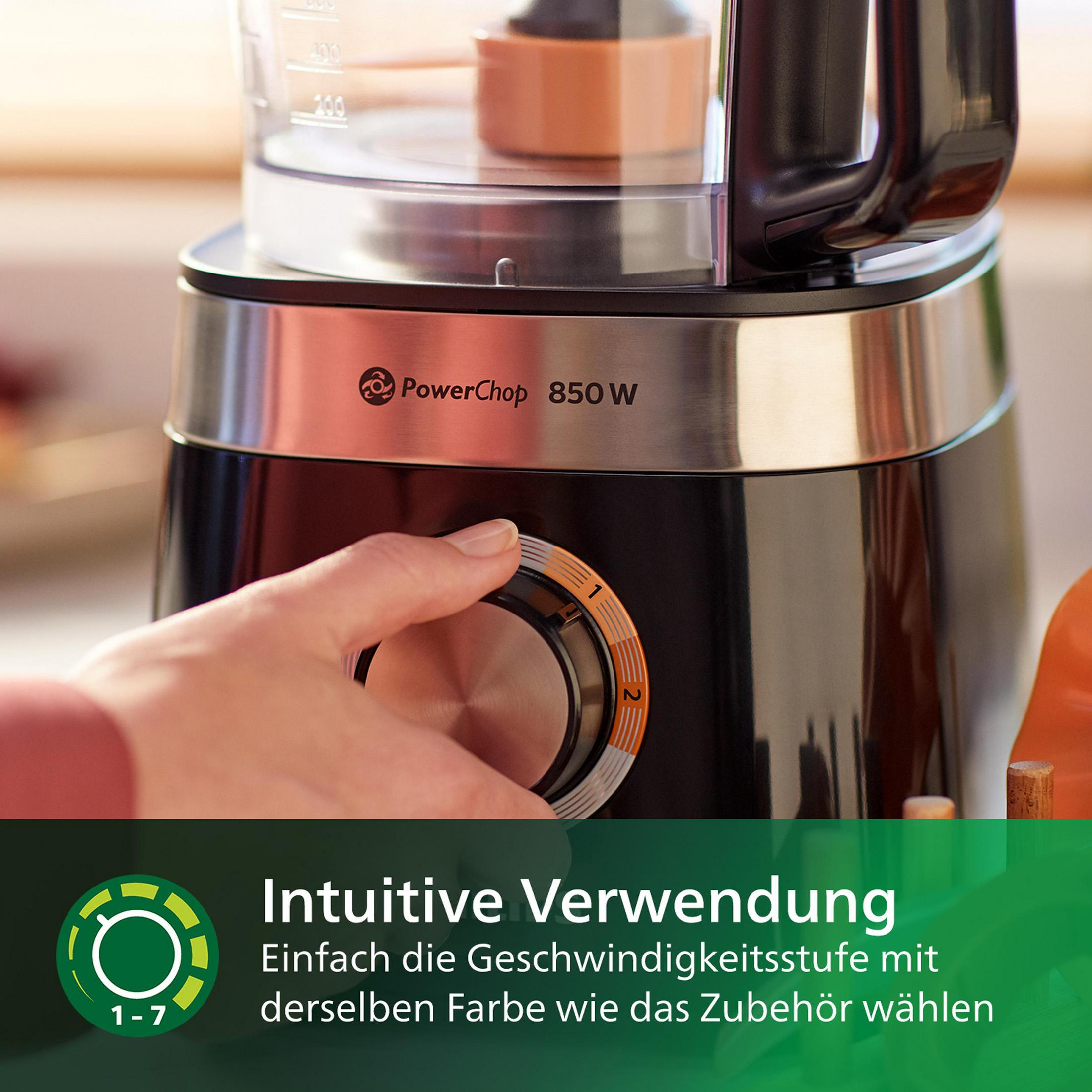 Eine Person benutzt einen schwarzen und silbernen Foodprozessor, der Drehregler ist im Fokus.