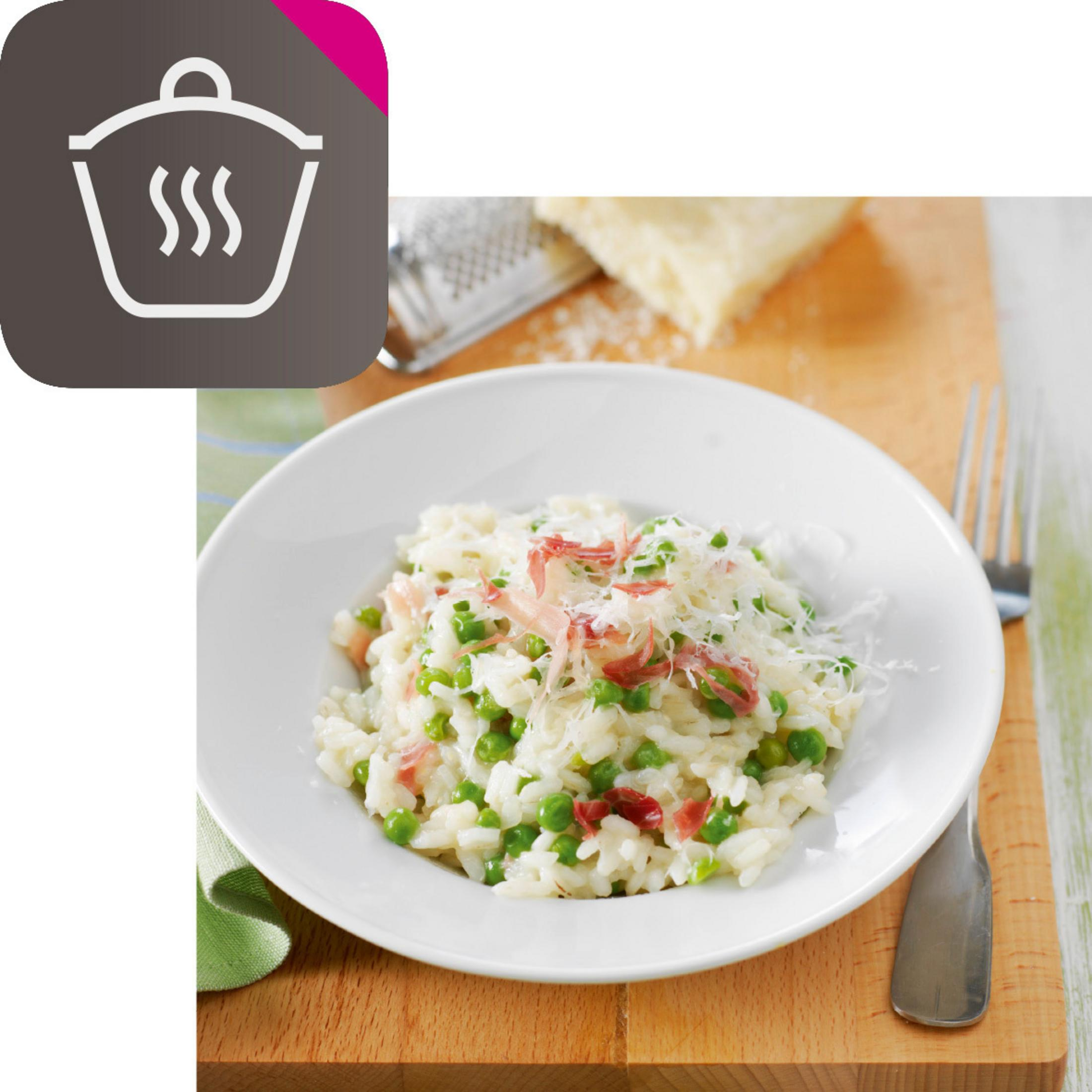 Teller mit Risotto mit Erbsen und Prosciutto. Geriebener Käse oben drauf.