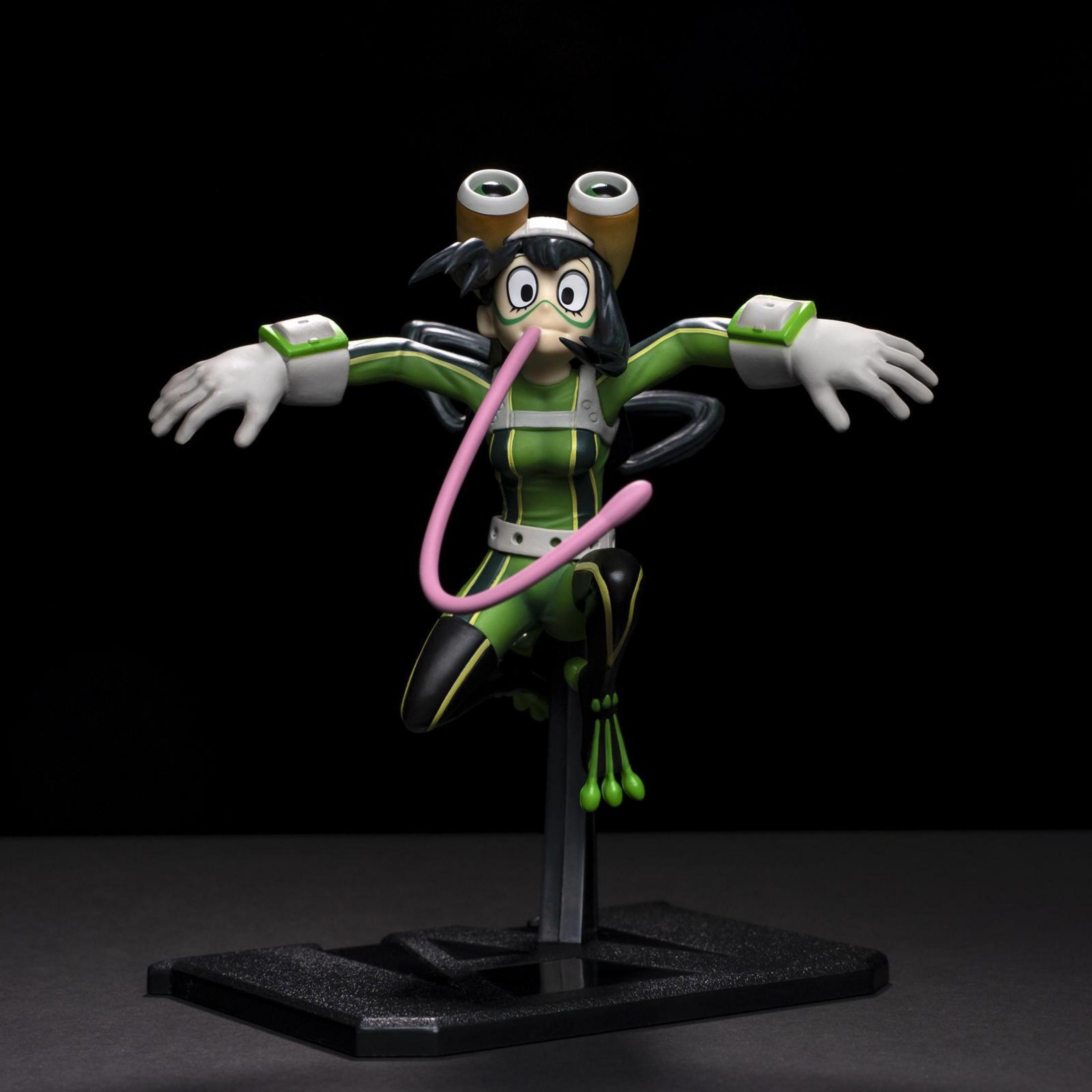 Eine Figur einer grünen Superheldin mit langer rosa Zunge und ausgestreckten Armen.