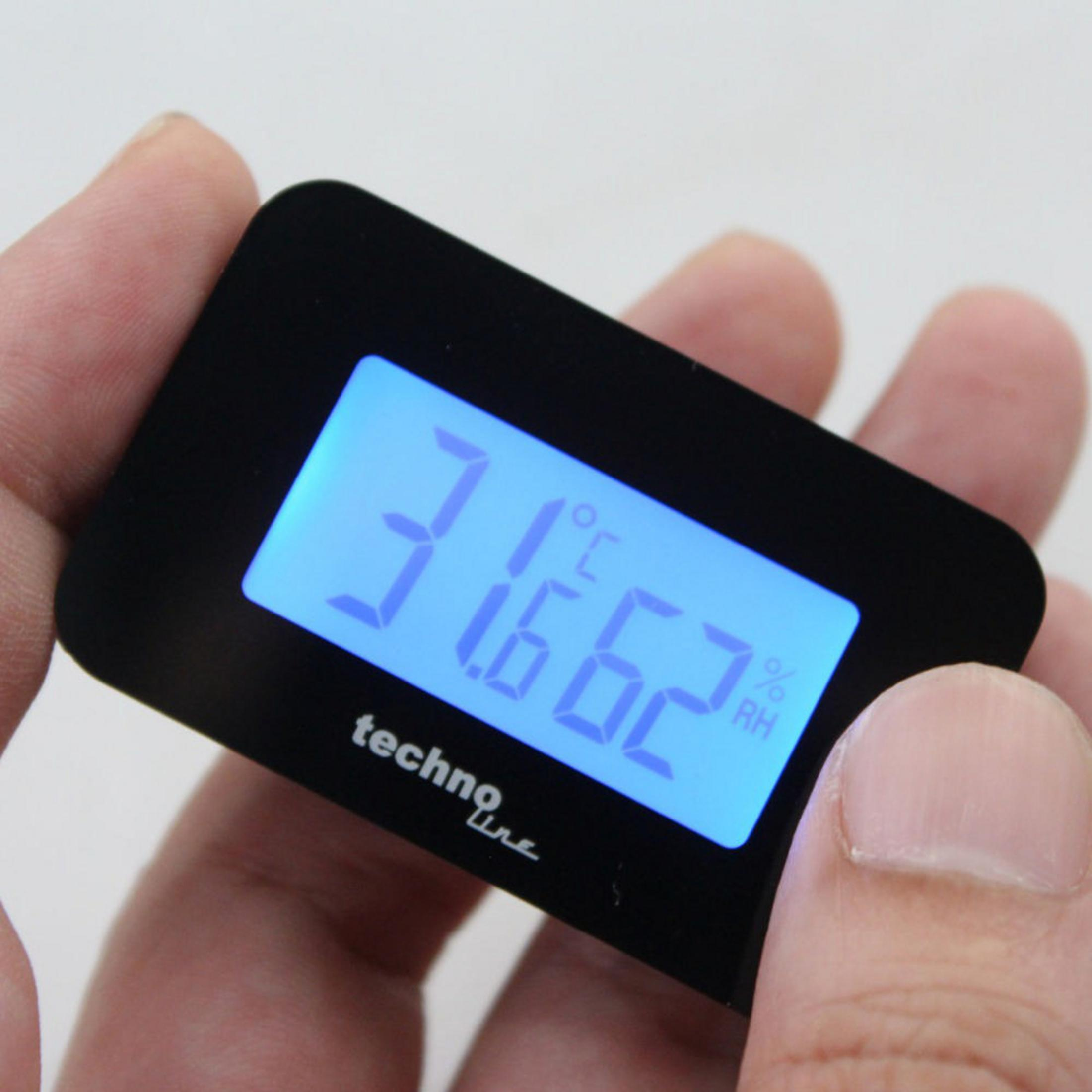 Ein schwarzes Digitaldisplay mit Zahlen. Es zeigt 31,6 °C und 62 % rF an. Von einer Hand gehalten.