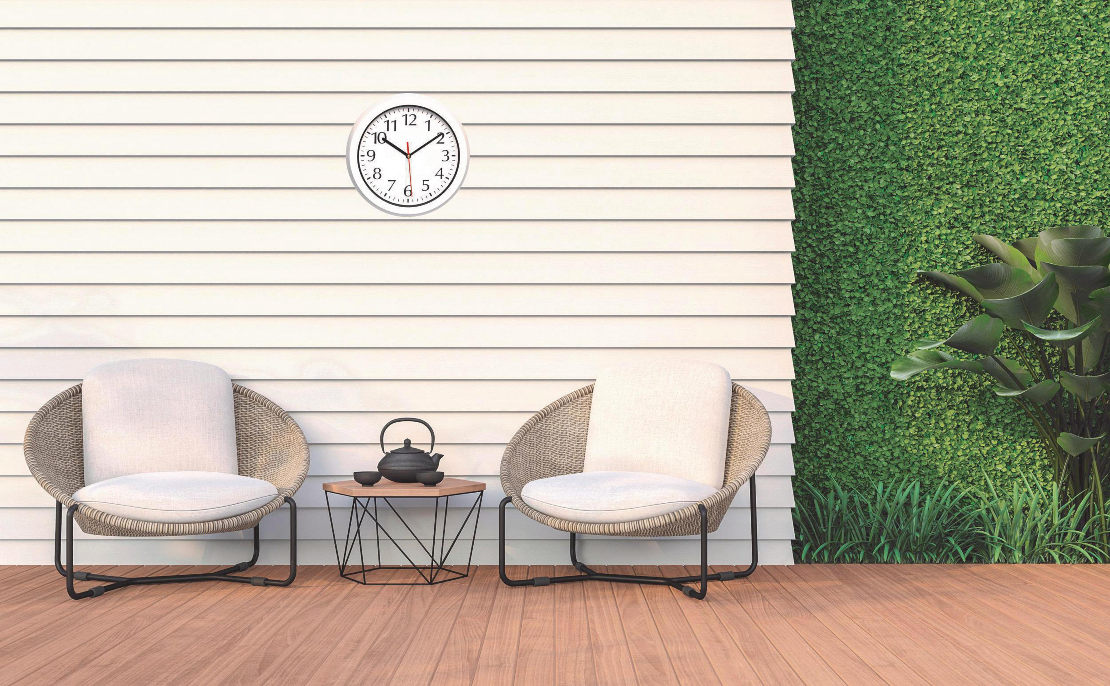 Terrassenszene. Weiße Wand mit Uhr, zwei Stühlen, Tisch mit Teekanne und Tassen, grüne Wand.