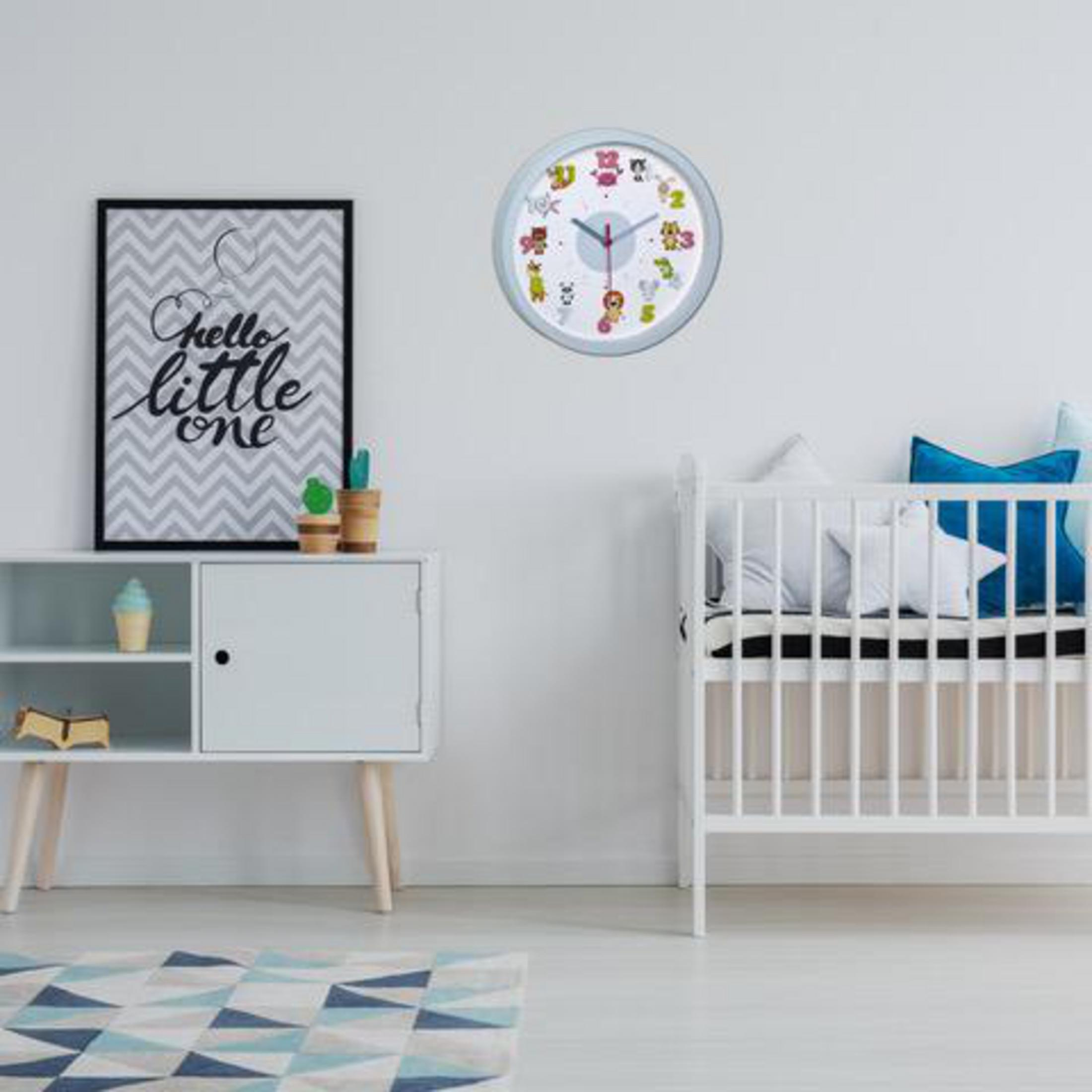 Ein Babyzimmer mit einer Uhr, einem Kinderbett und einem Schild 'Hello little one'.