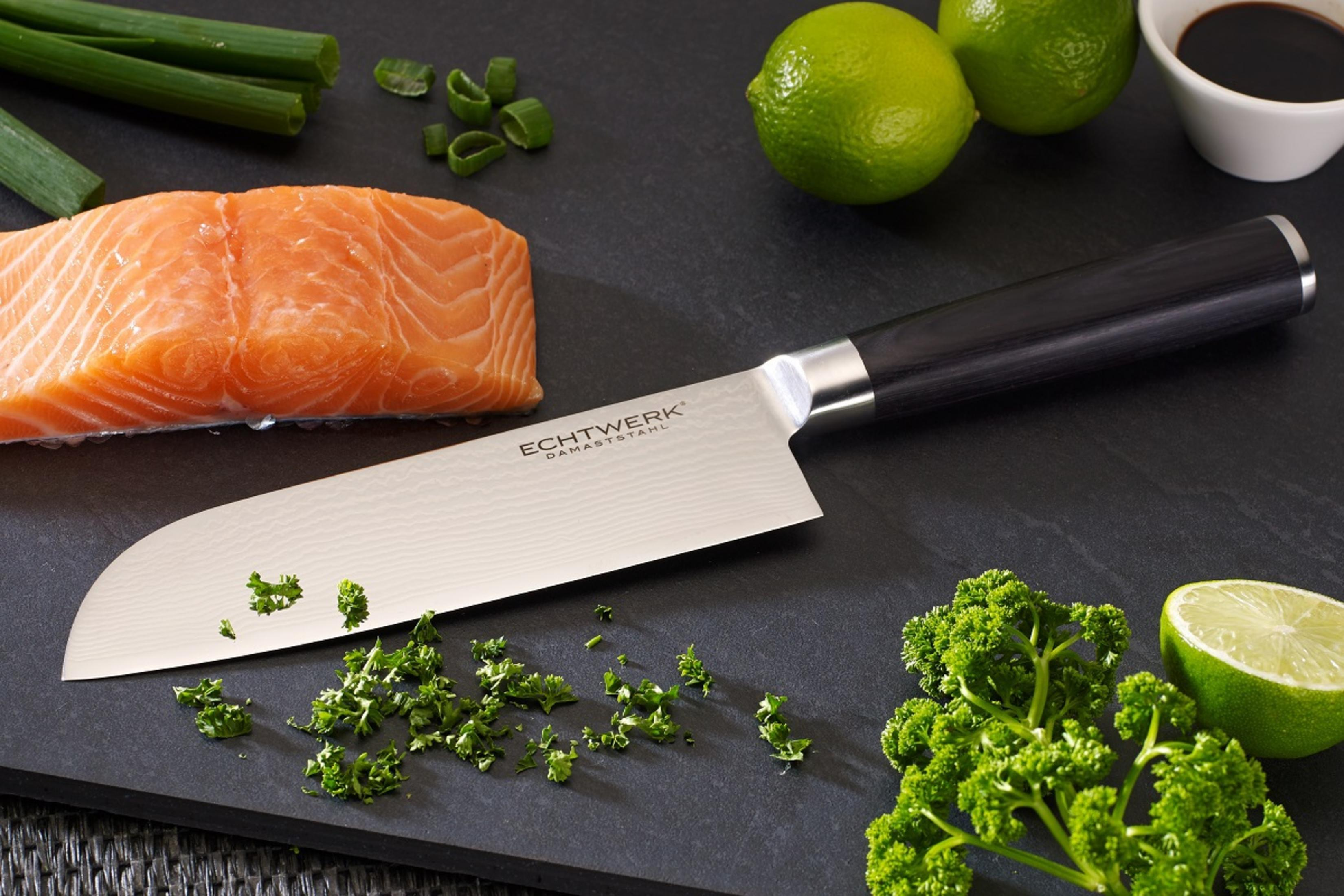 Lachs, Messer, Petersilie und Limette auf schwarzem Schneidebrett.