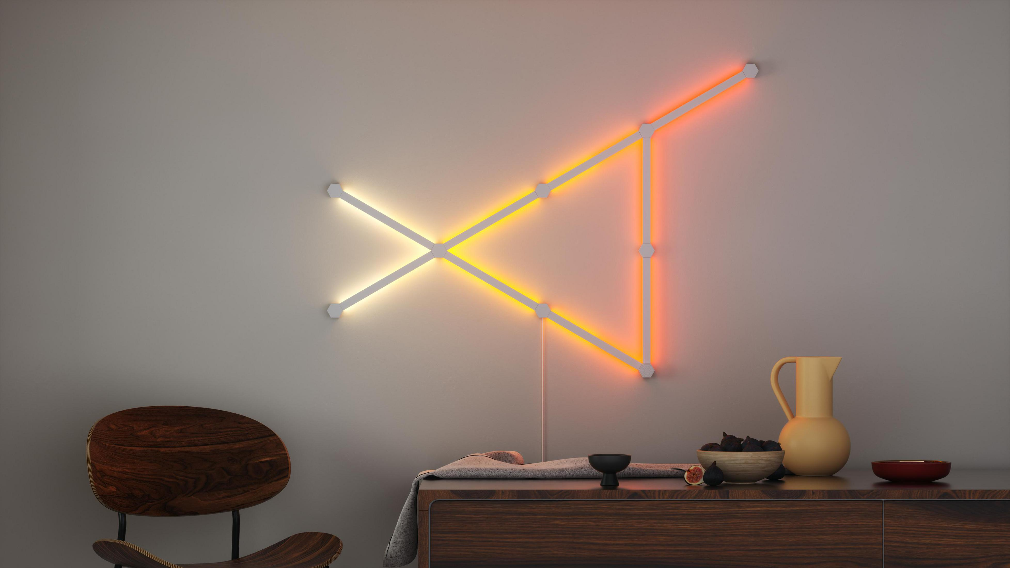 Gri bir duvarda geometrik neon ışıklandırma. Önünde objeler olan ahşap masa. Sıcak renkler.
