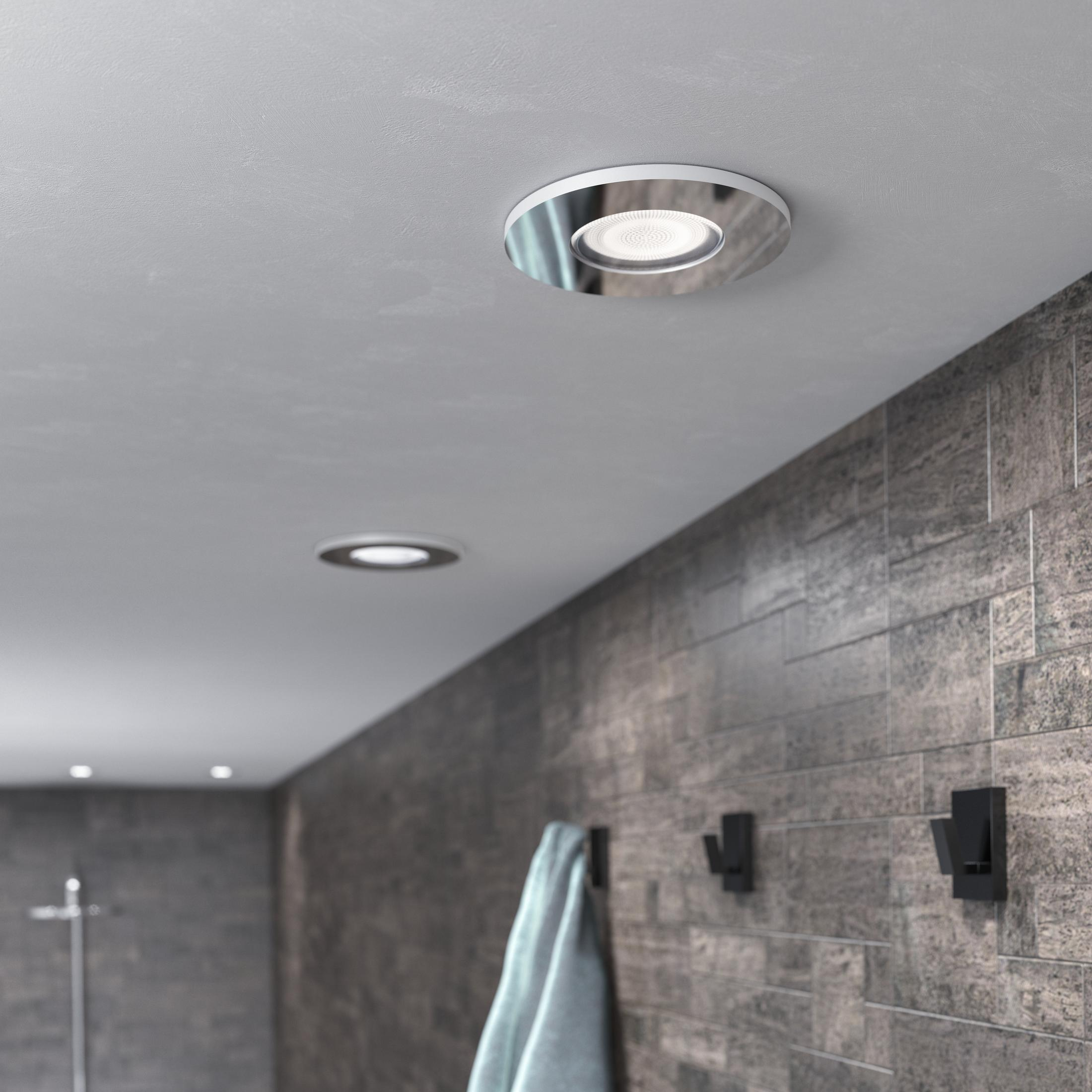 Soffitto con due faretti. Parete in piastrelle grigie con asciugamano e ganci.