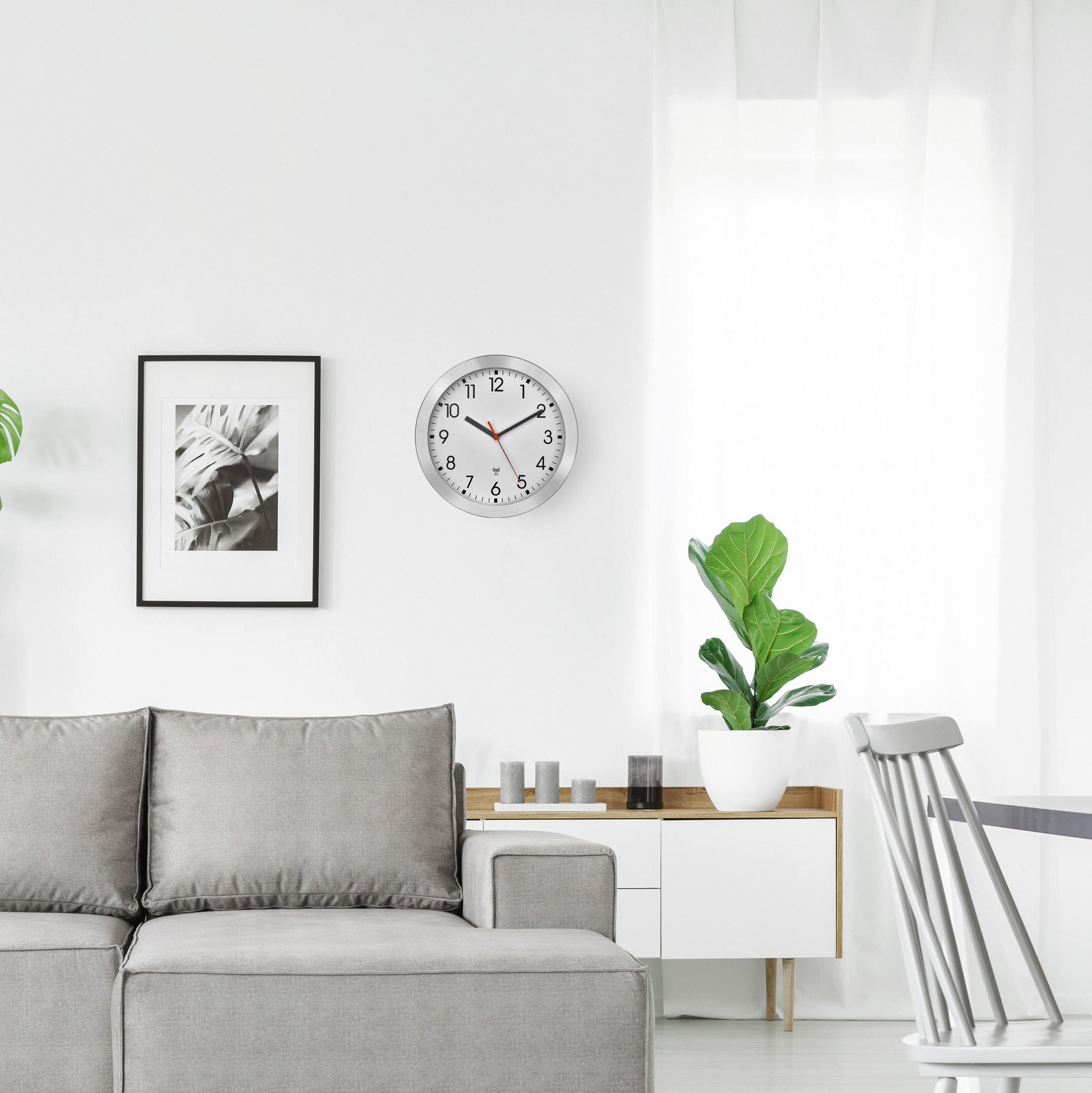 Wohnzimmer mit grauem Sofa, gerahmtem Bild, Uhr und weißem Schrank.