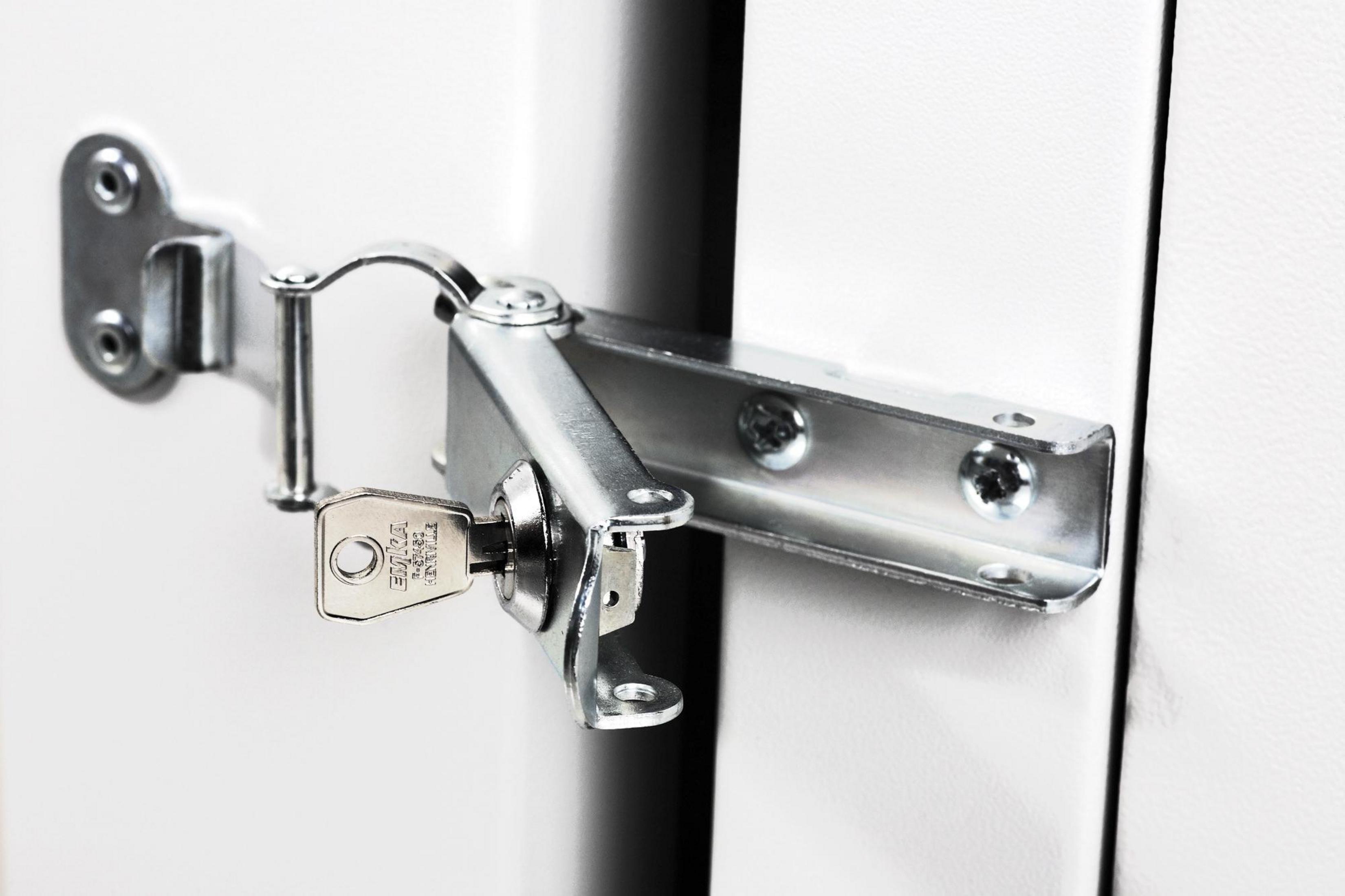 Primo piano di un fermo metallico con chiave, su una porta bianca.