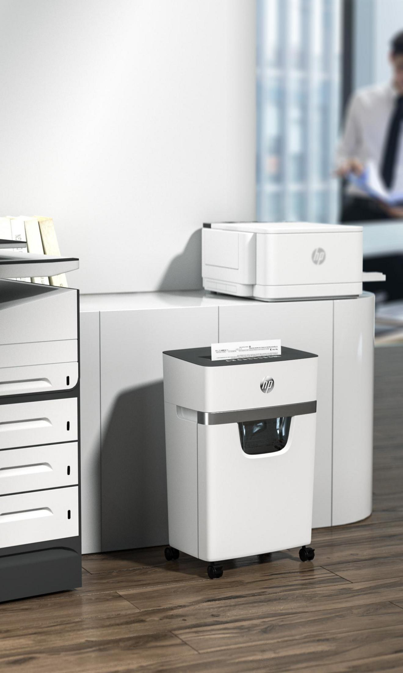 Biała niszczarka, drukarka i jednostka magazynująca na drewnie. Mężczyzna w tle.