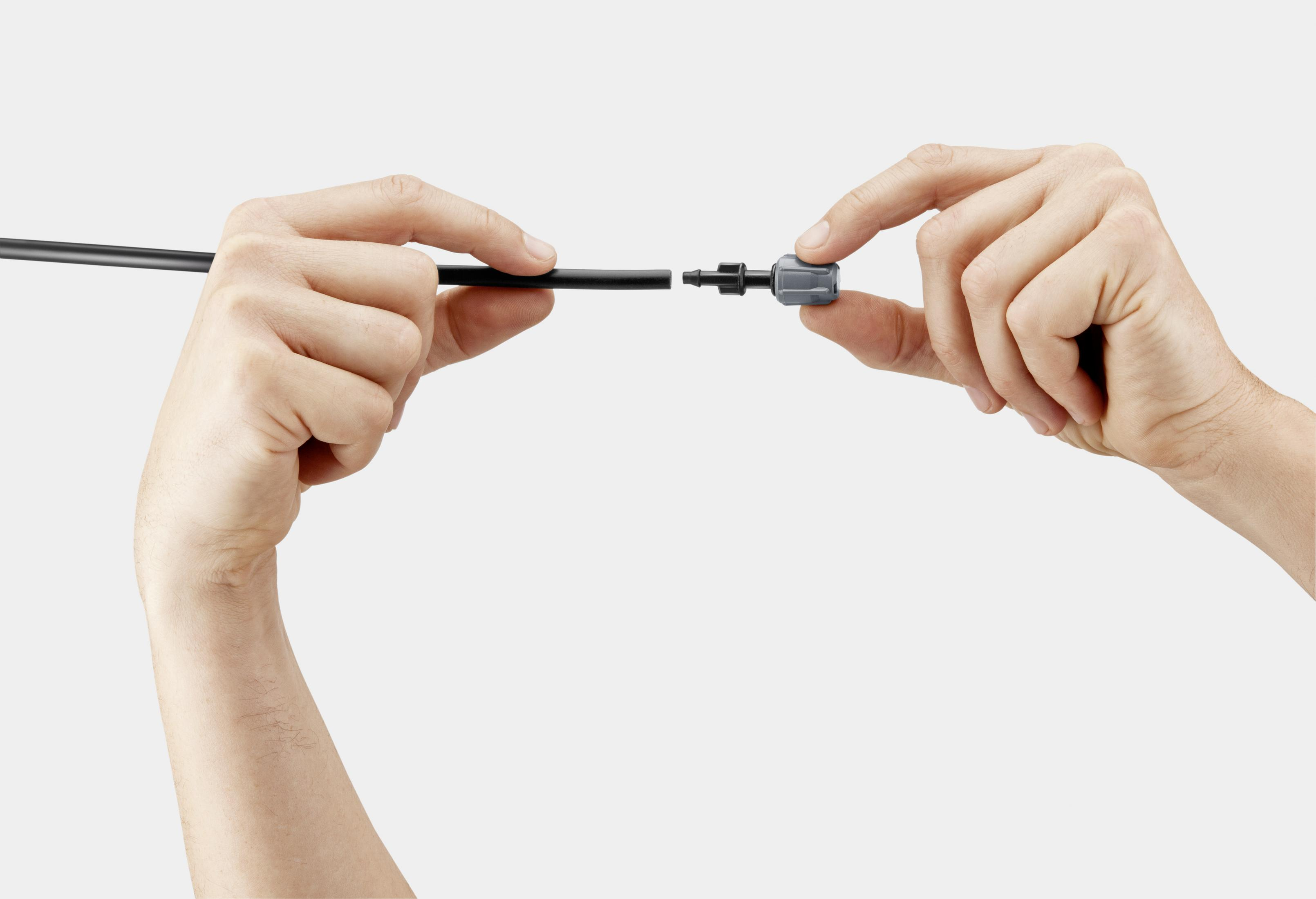 Manos conectando una manguera negra a un conector gris.