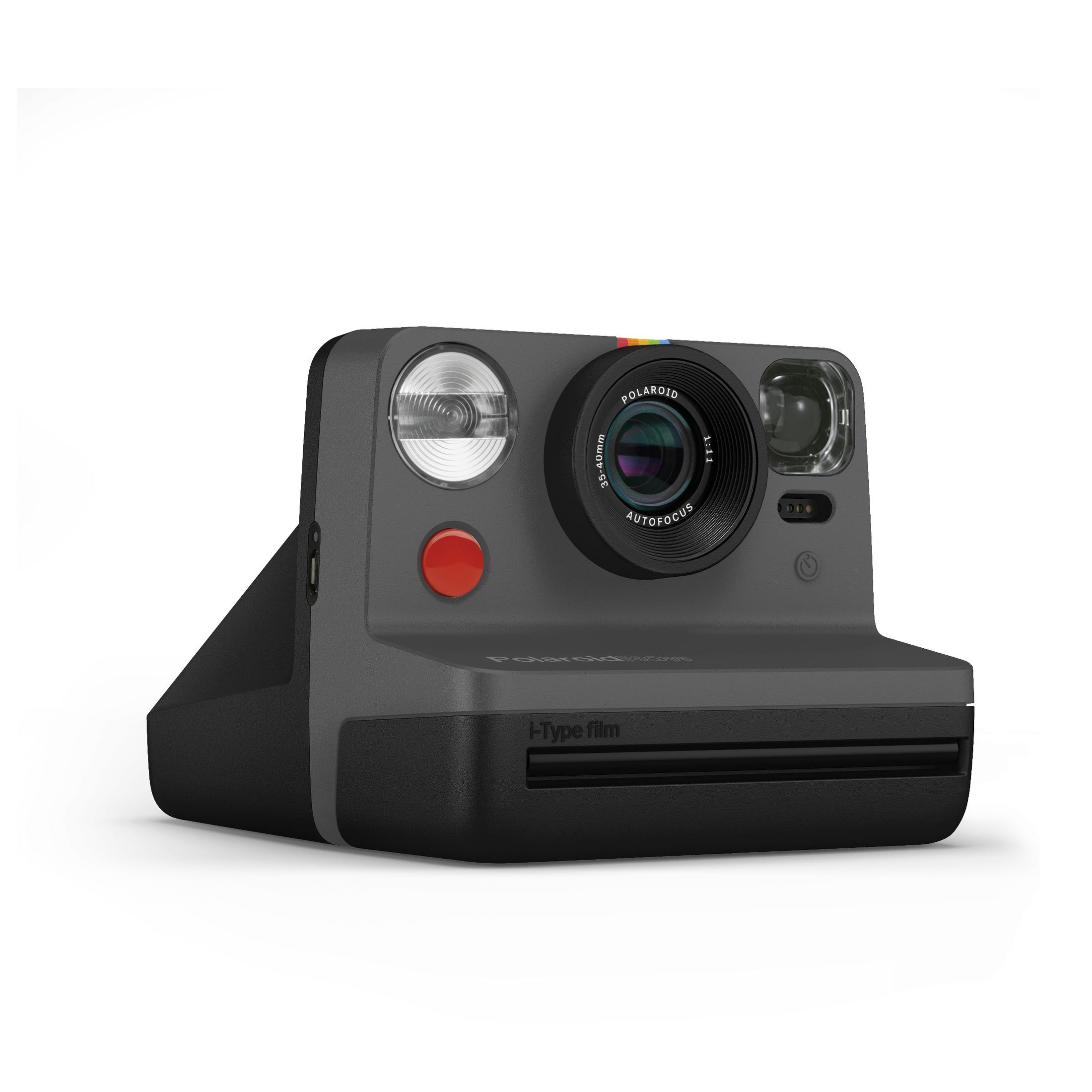 Cámara instantánea Polaroid gris oscuro. Tiene un botón rojo, una lente, un flash y una base negra.
