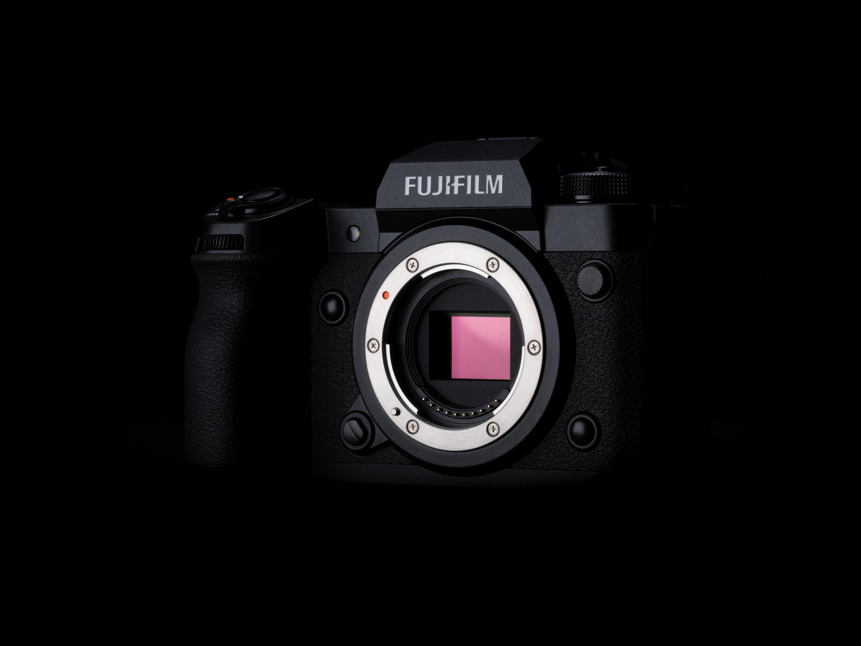 Una cámara Fujifilm negra con un sensor rosa sobre un fondo negro oscuro.