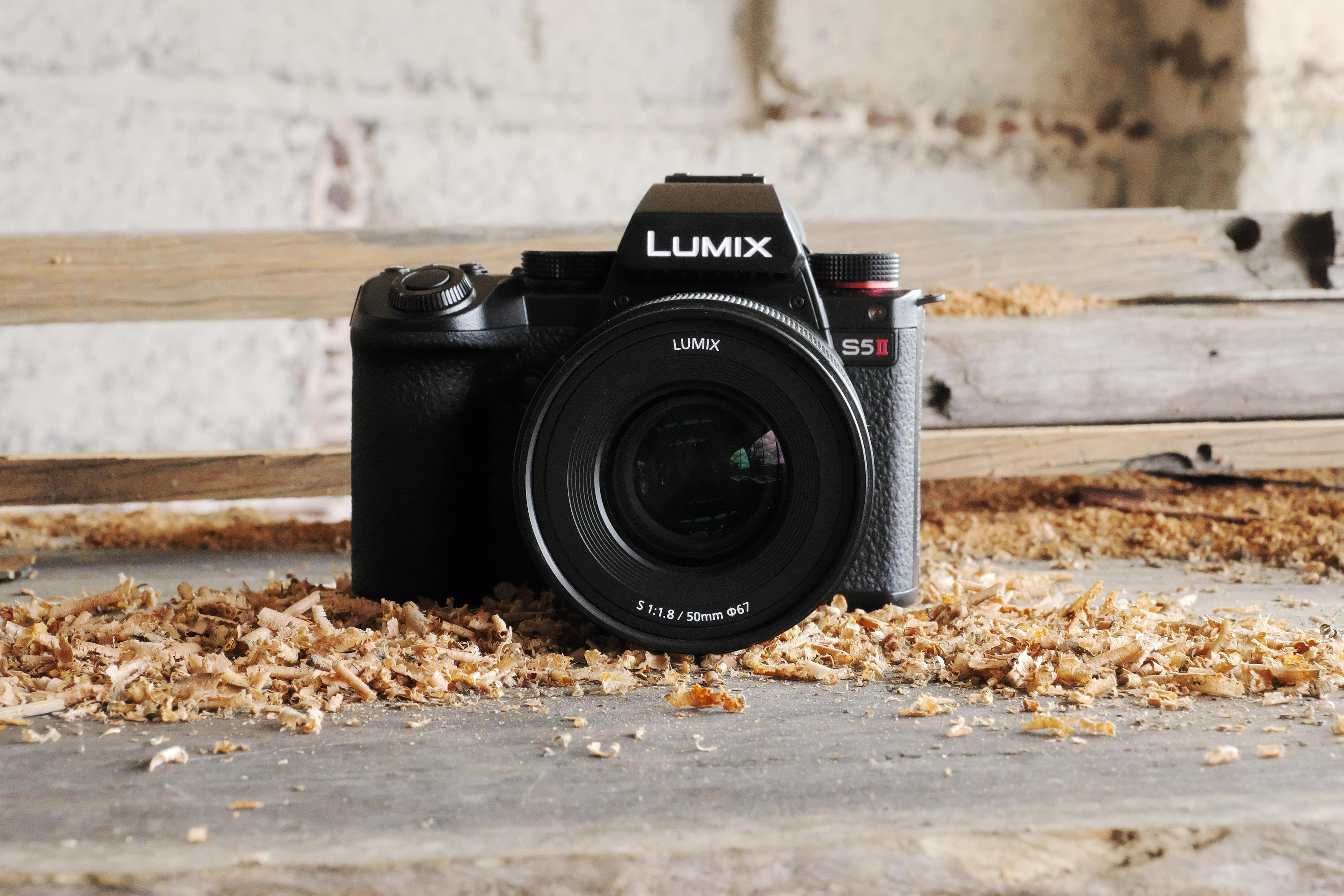 Appareil photo Lumix S5 II noir sur une surface en bois avec des copeaux de bois, objectif face avant.