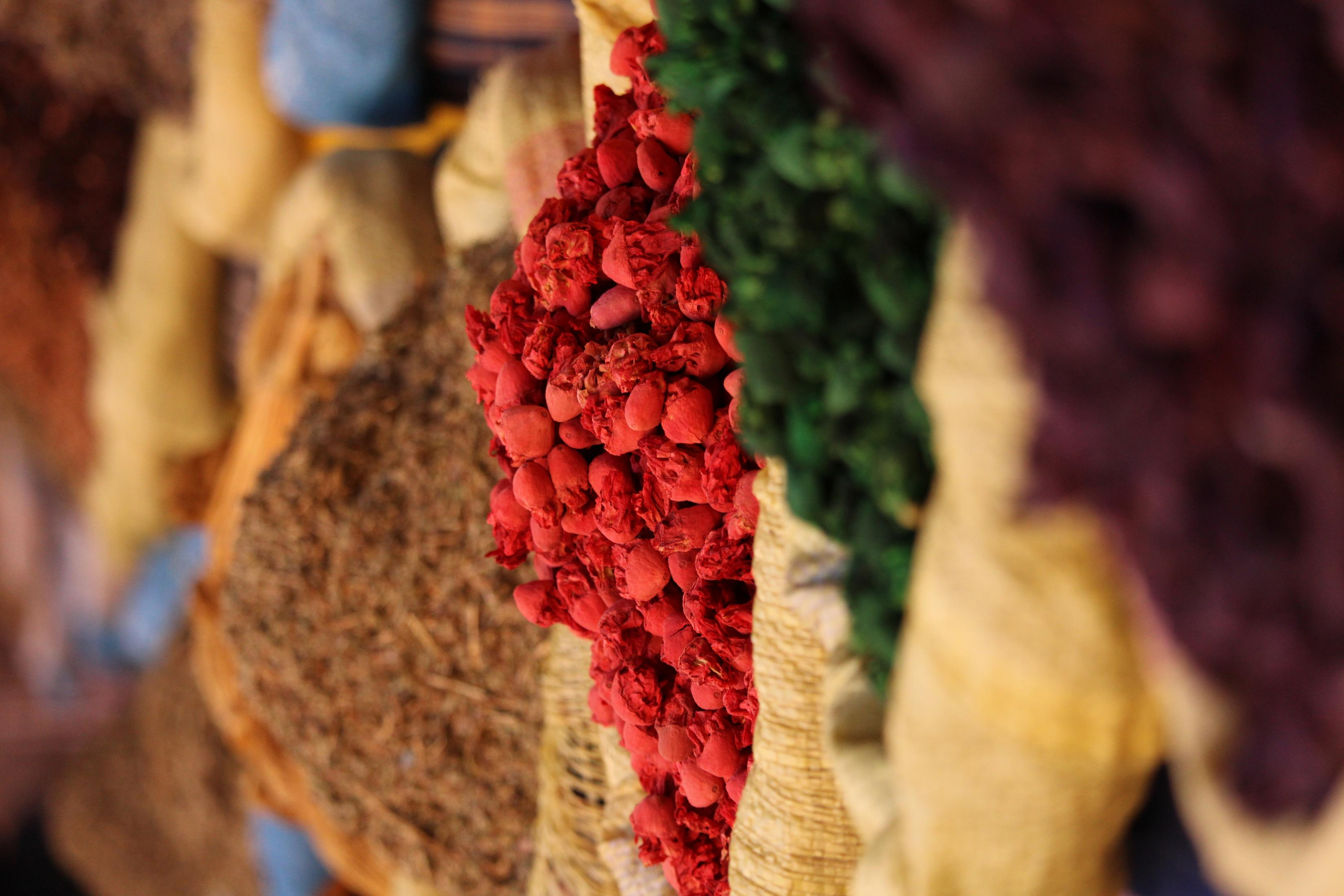 Nahaufnahme von bunten Gewürzbeuteln. Rote Pfefferkörner sind im Fokus, andere Gewürze im Hintergrund.