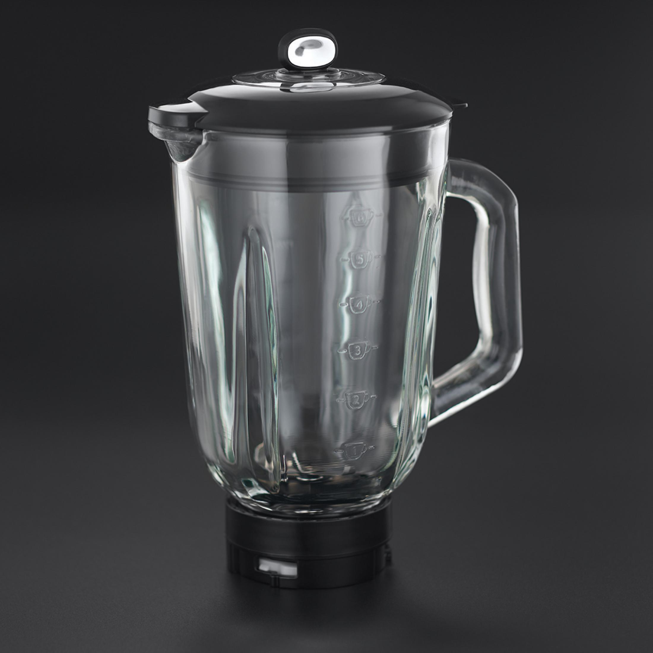 Siyah kapaklı şeffaf cam bir blender sürahisi koyu bir yüzeyde duruyor.