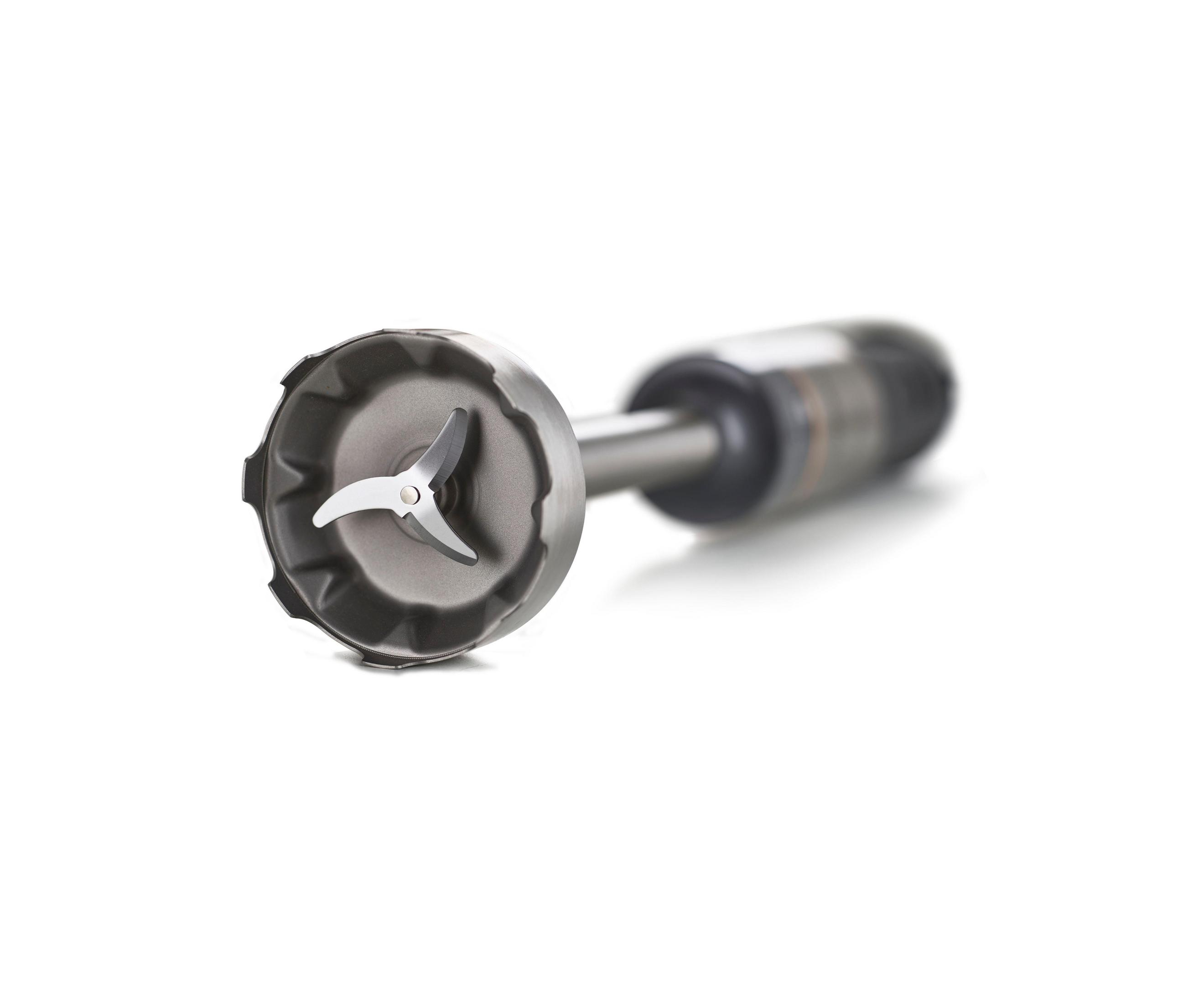 Close-up van de meskop van een staafmixer, schuin naar de kijker. Het mes is zilver, de bescherming donkergrijs.