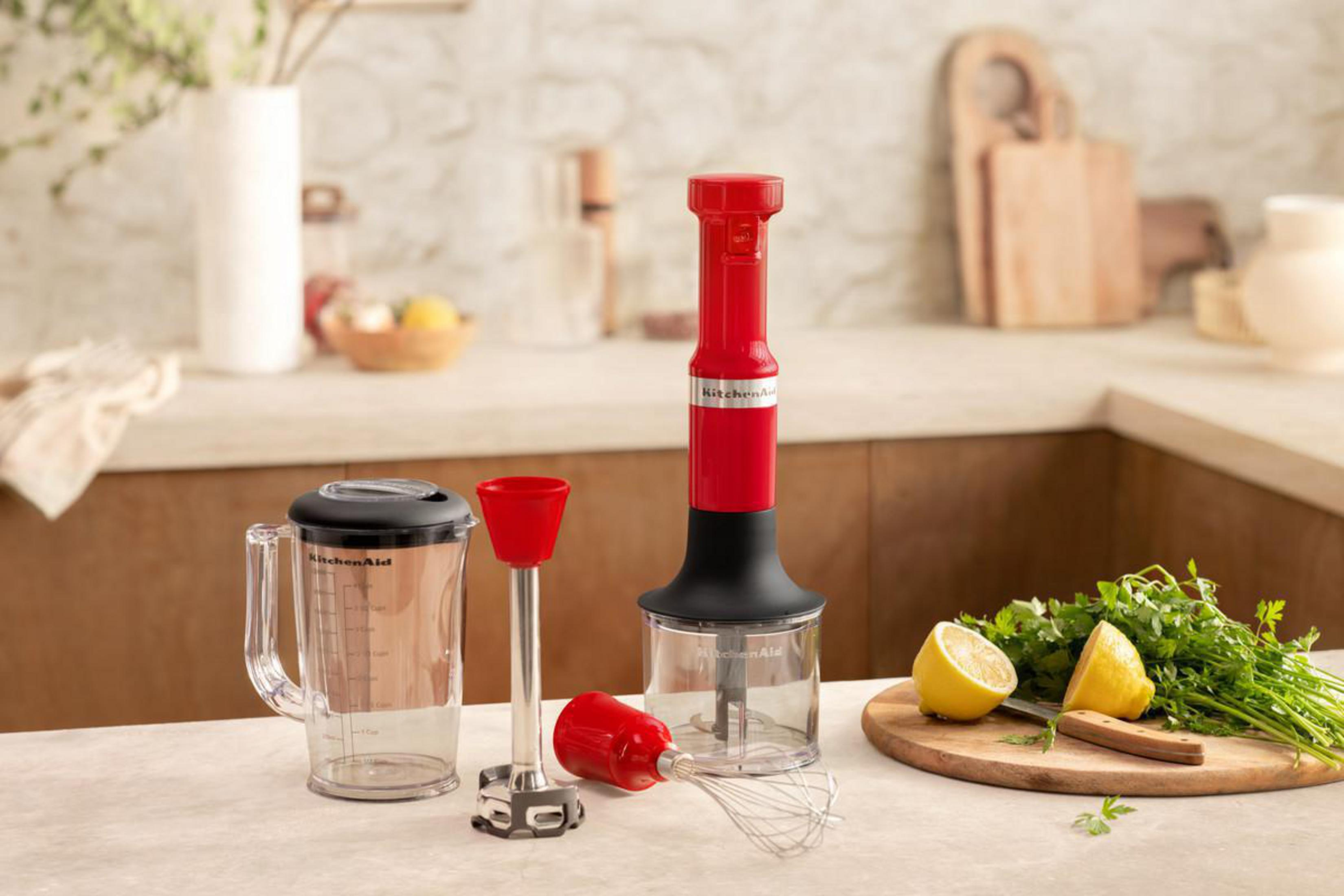 Czerwony blender KitchenAid z akcesoriami na blacie kuchennym.