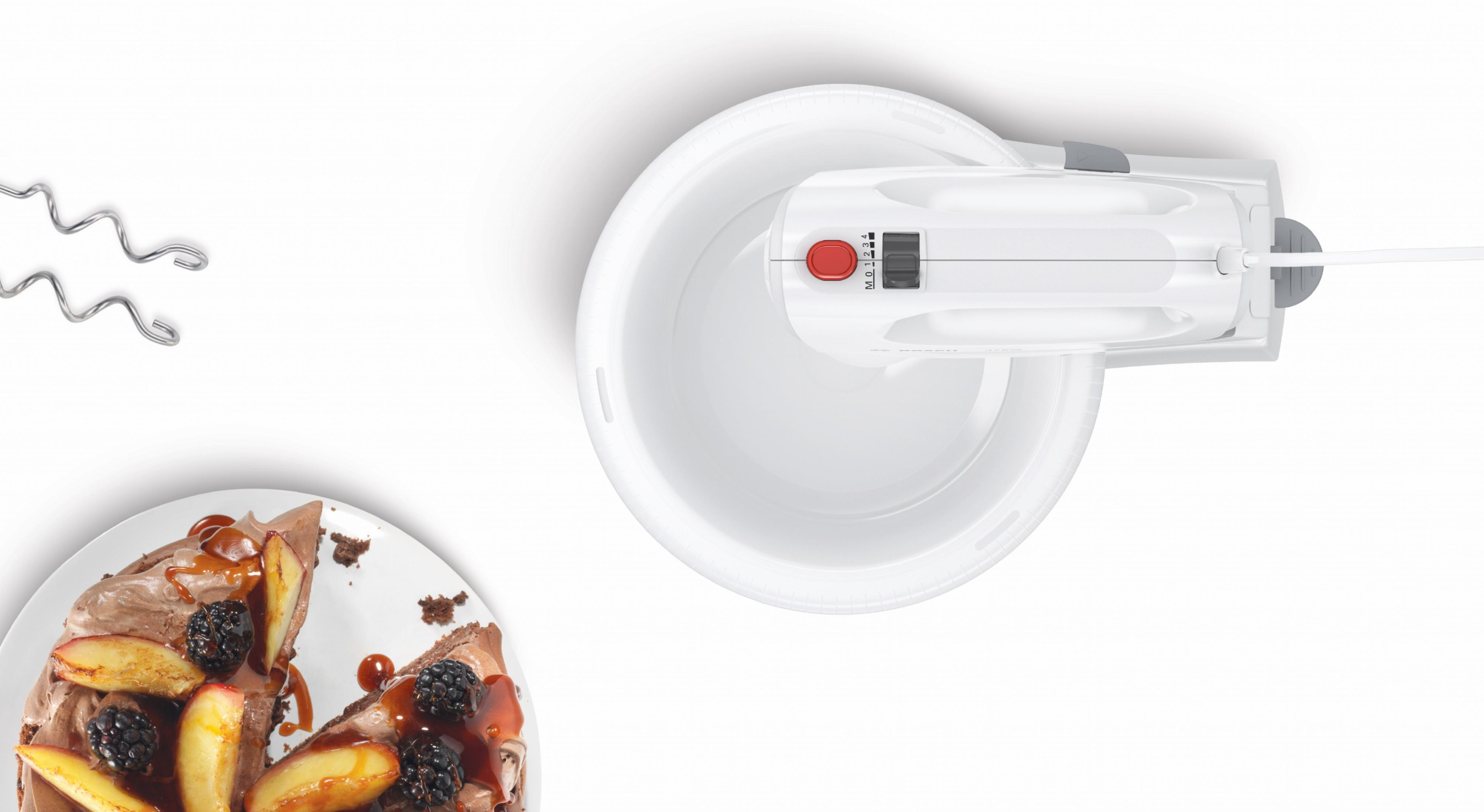 Biały mikser ręczny w białej misce z kawałkiem ciasta i nakładkami do ubijania na białym tle.