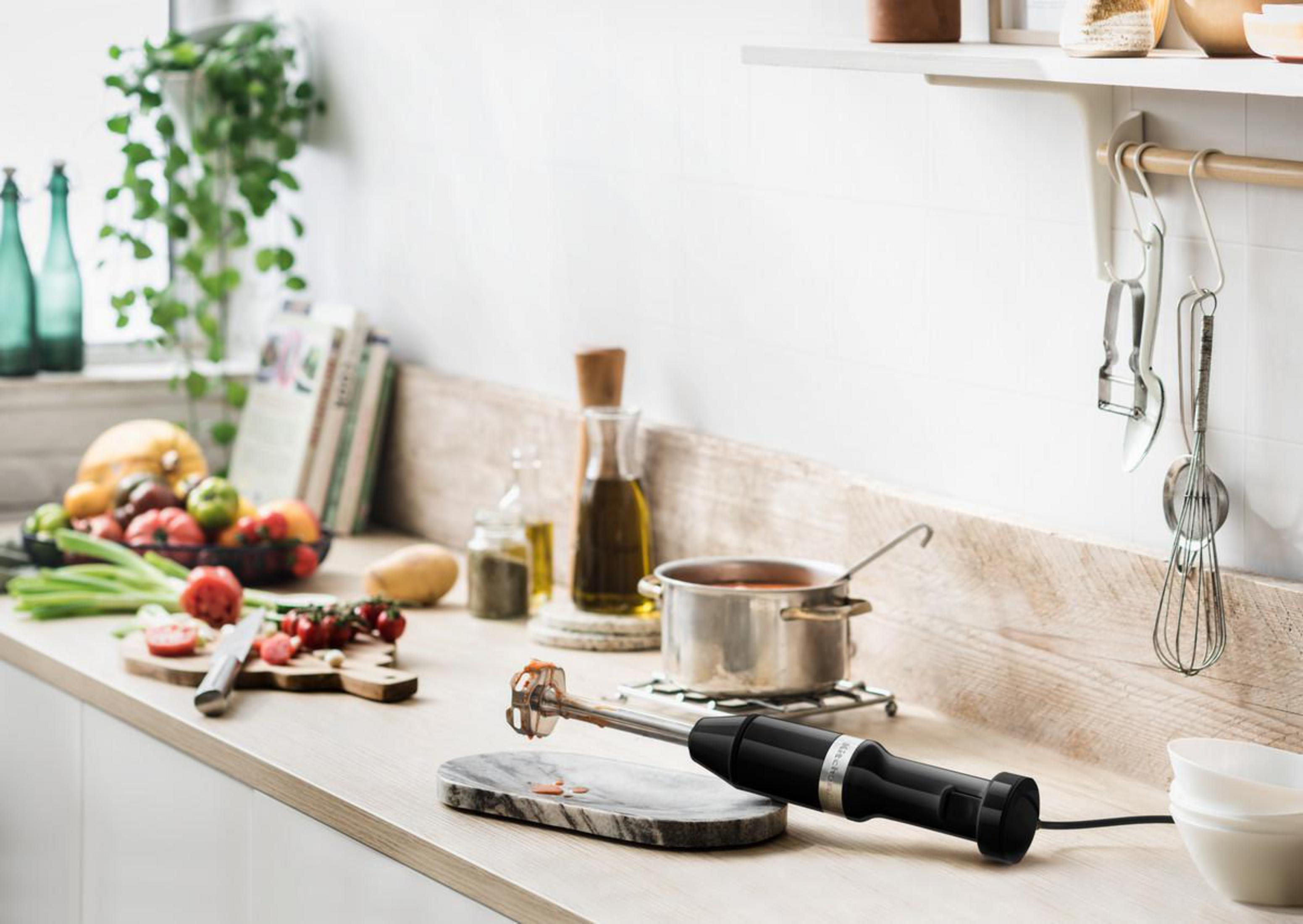 Scena w kuchni: blender, składniki i garnek na drewnianym blacie.