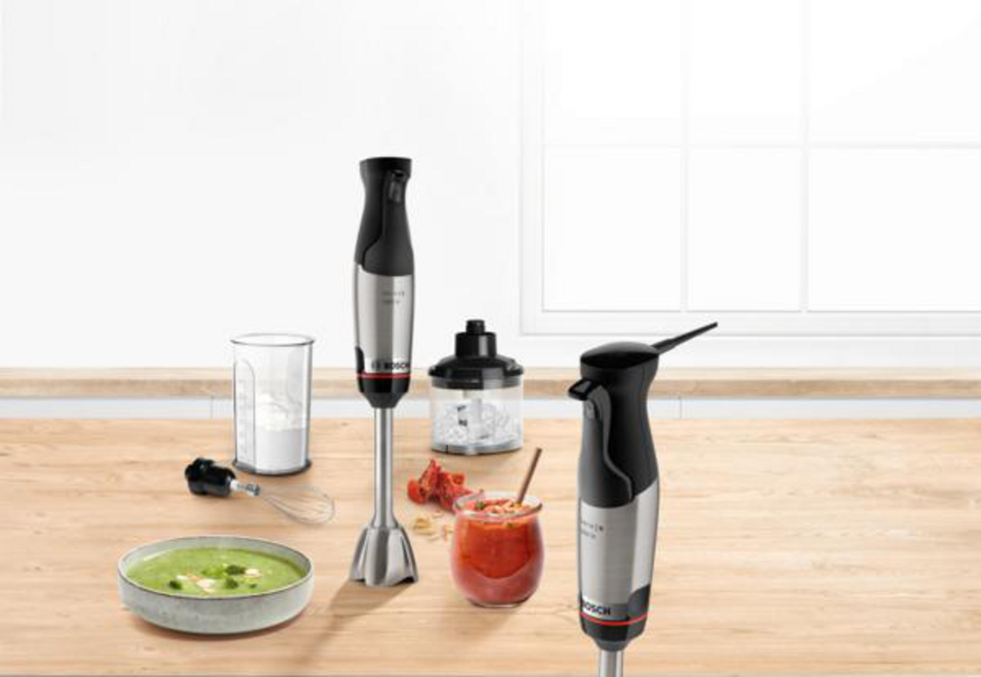 Un tavolo di legno con elettrodomestici da cucina. Include frullatori, cibo e ingredienti.