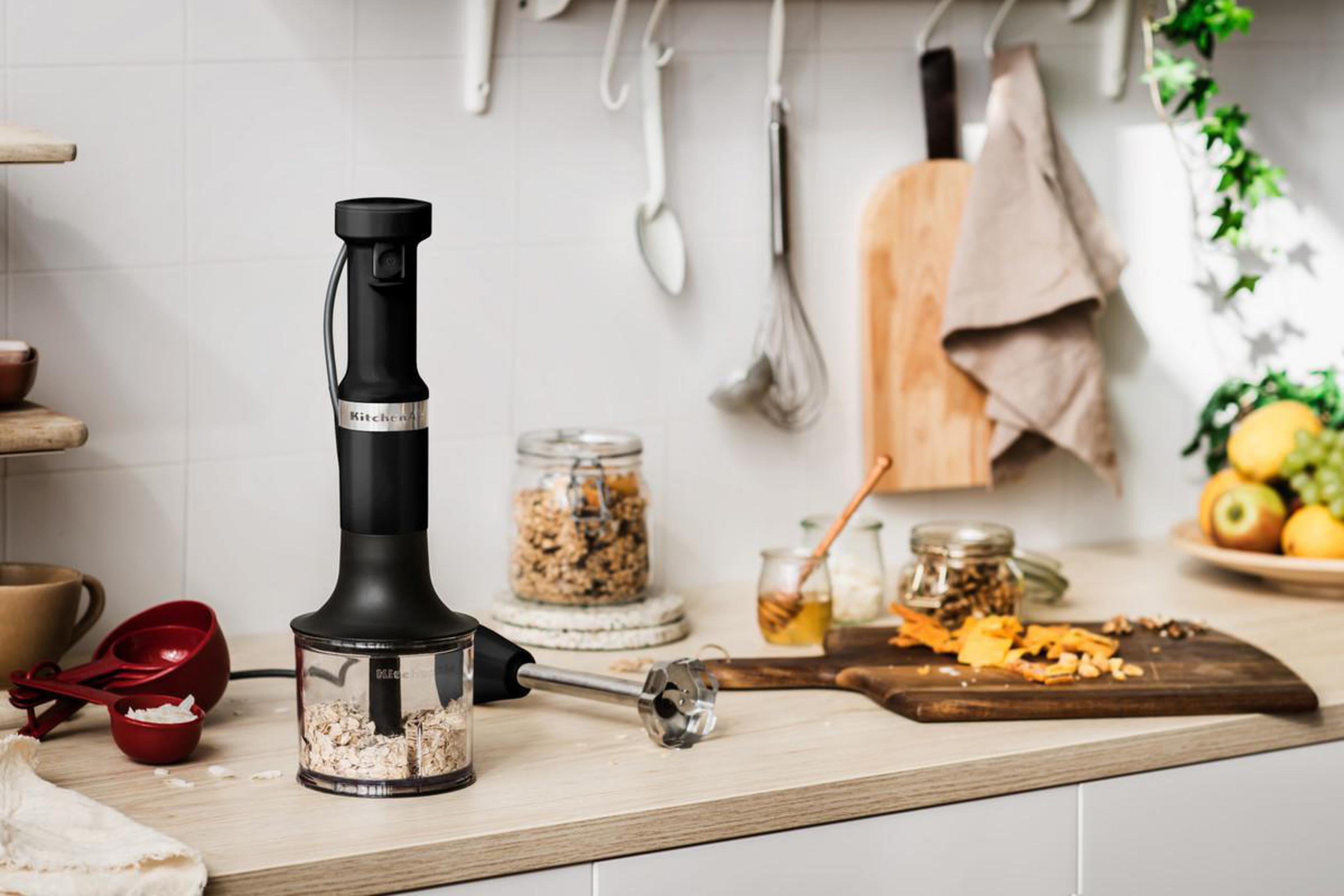 Black kitchen blender with a container of oats. A wooden board with ingredients.