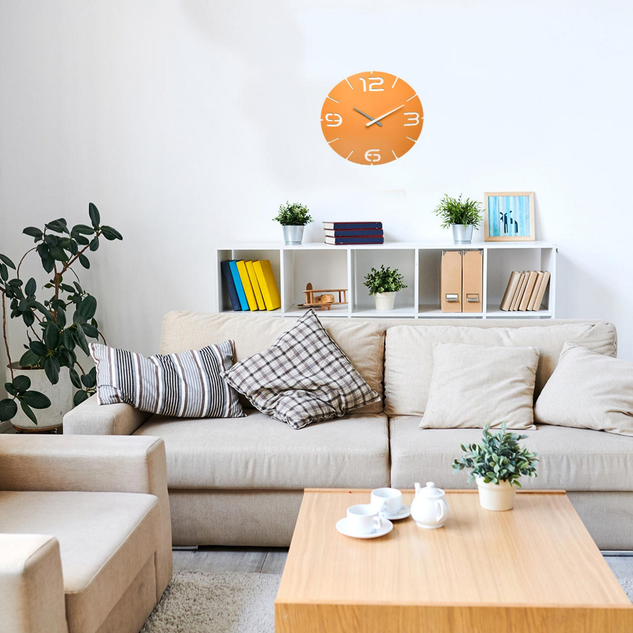 Orange Wanduhr über einem beigen Sofa mit Kissen, Couchtisch und Pflanzen.