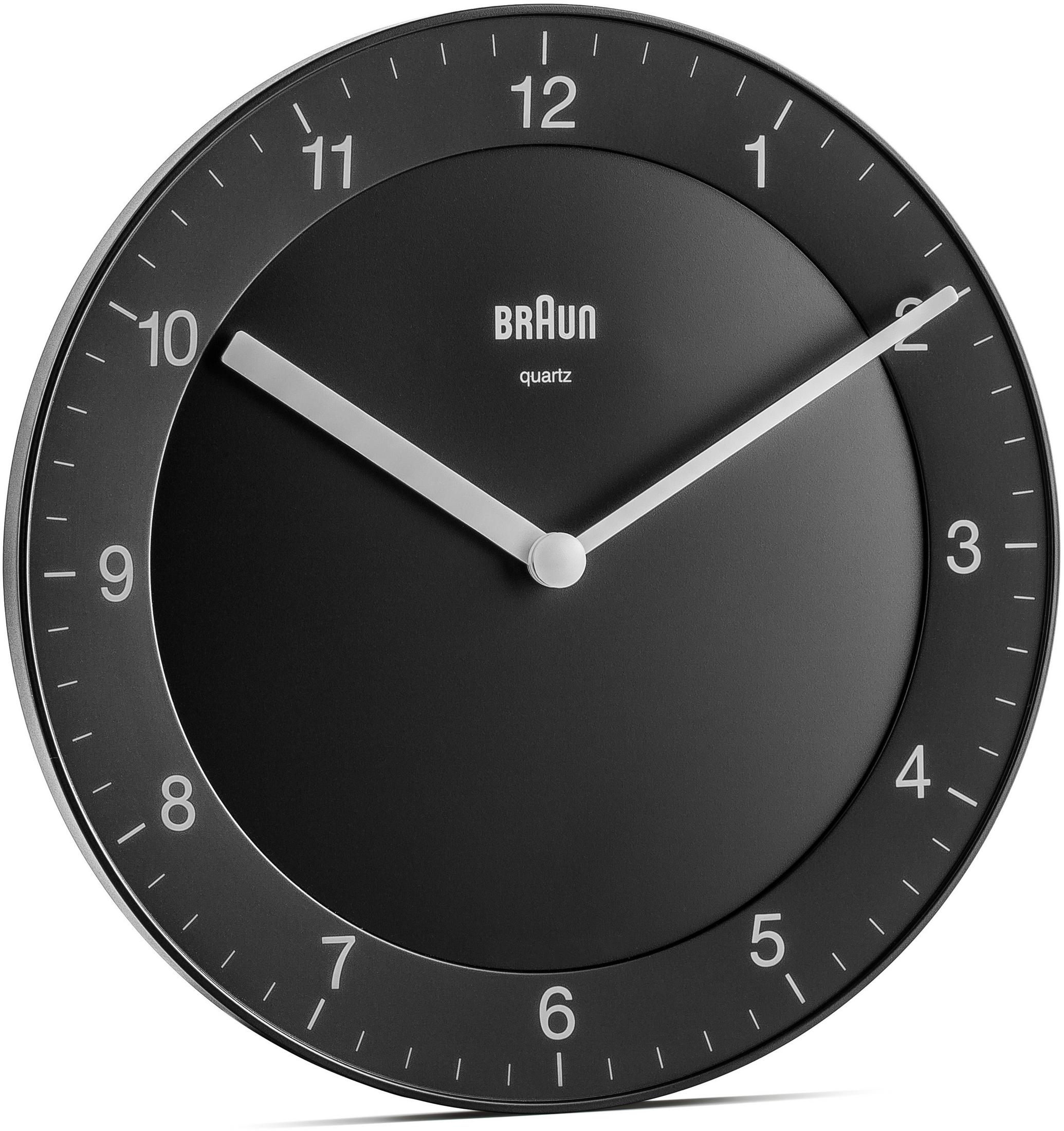 Eine schwarze Wanduhr mit weißen Zeigern und Ziffern. Die Marke 'Braun' ist sichtbar.