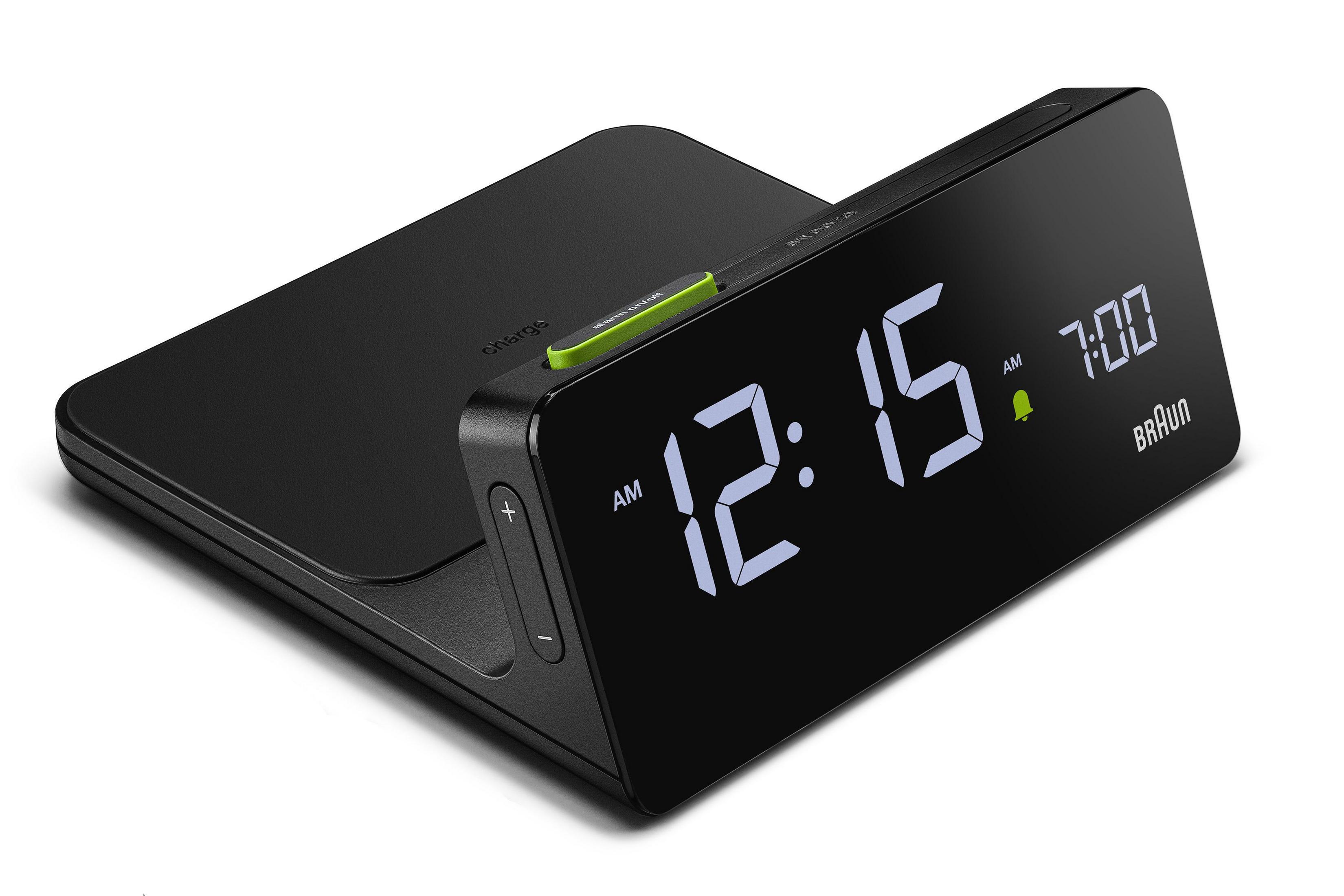 Ein schwarzer digitaler Wecker mit grüner Taste, zeigt 12:15 Uhr an.