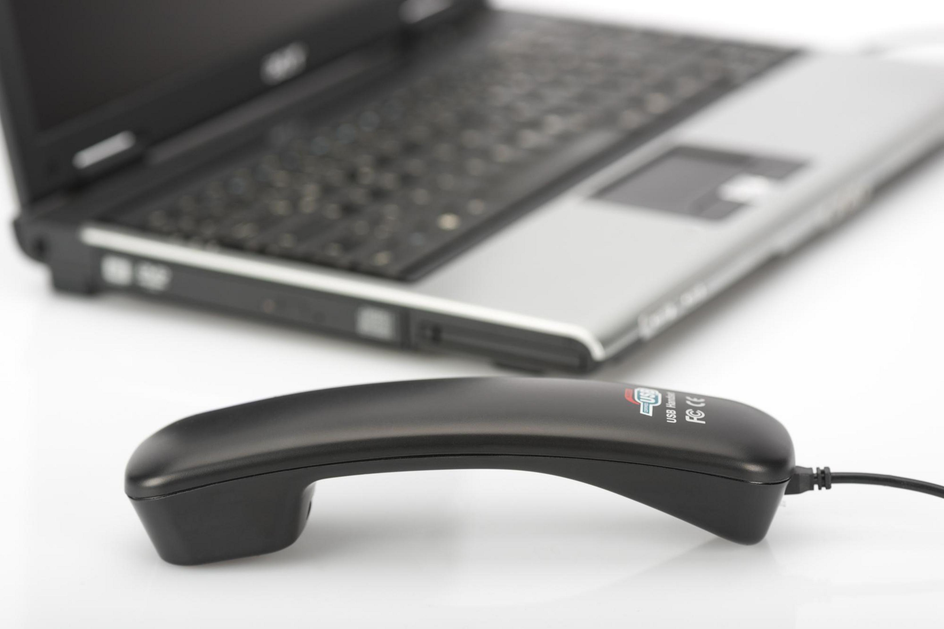 Schwarzer Telefonhörer vor einem Laptop. Der Laptop ist im Hintergrund.