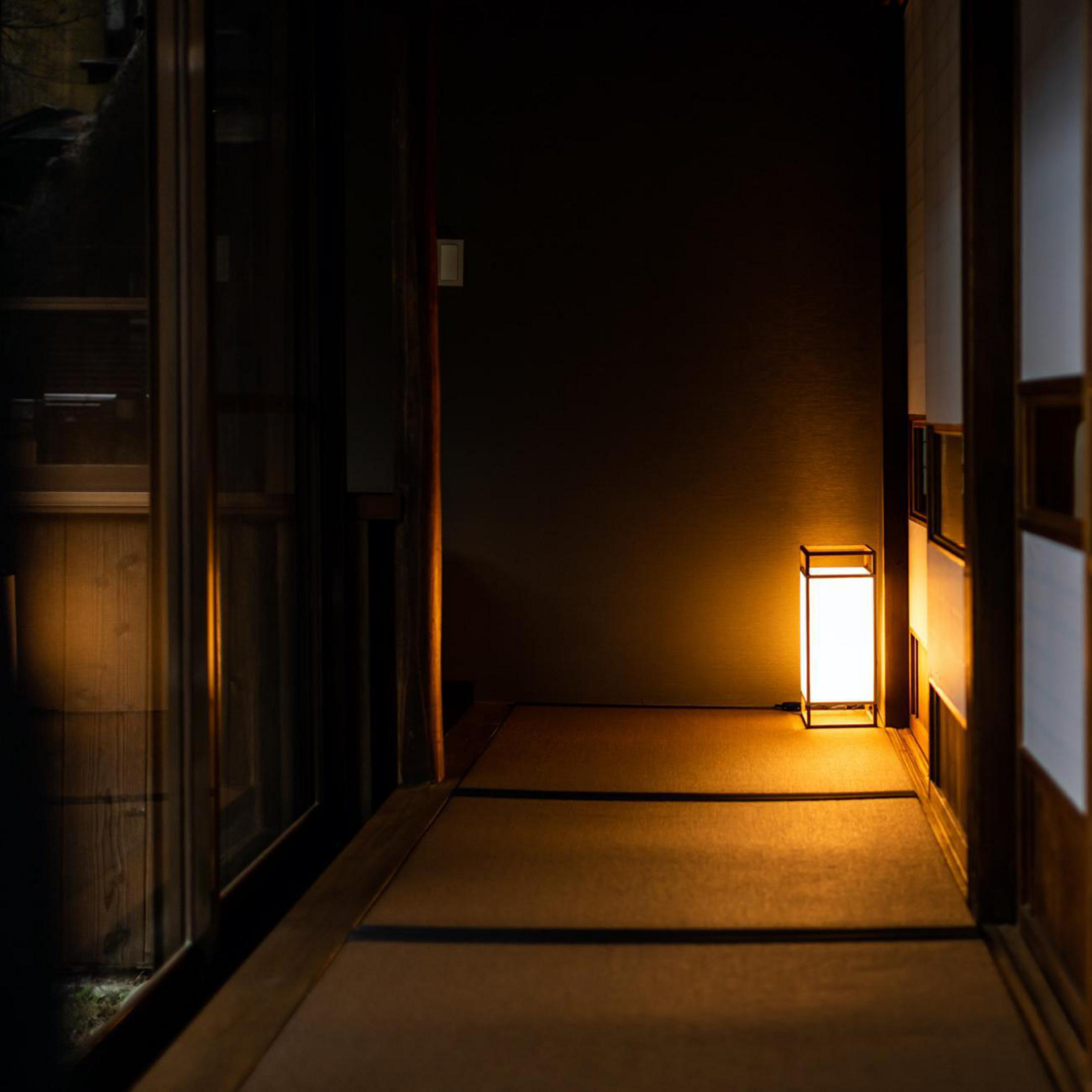 Corridoio illuminato con lampada. Il legno scuro incornicia la vista.