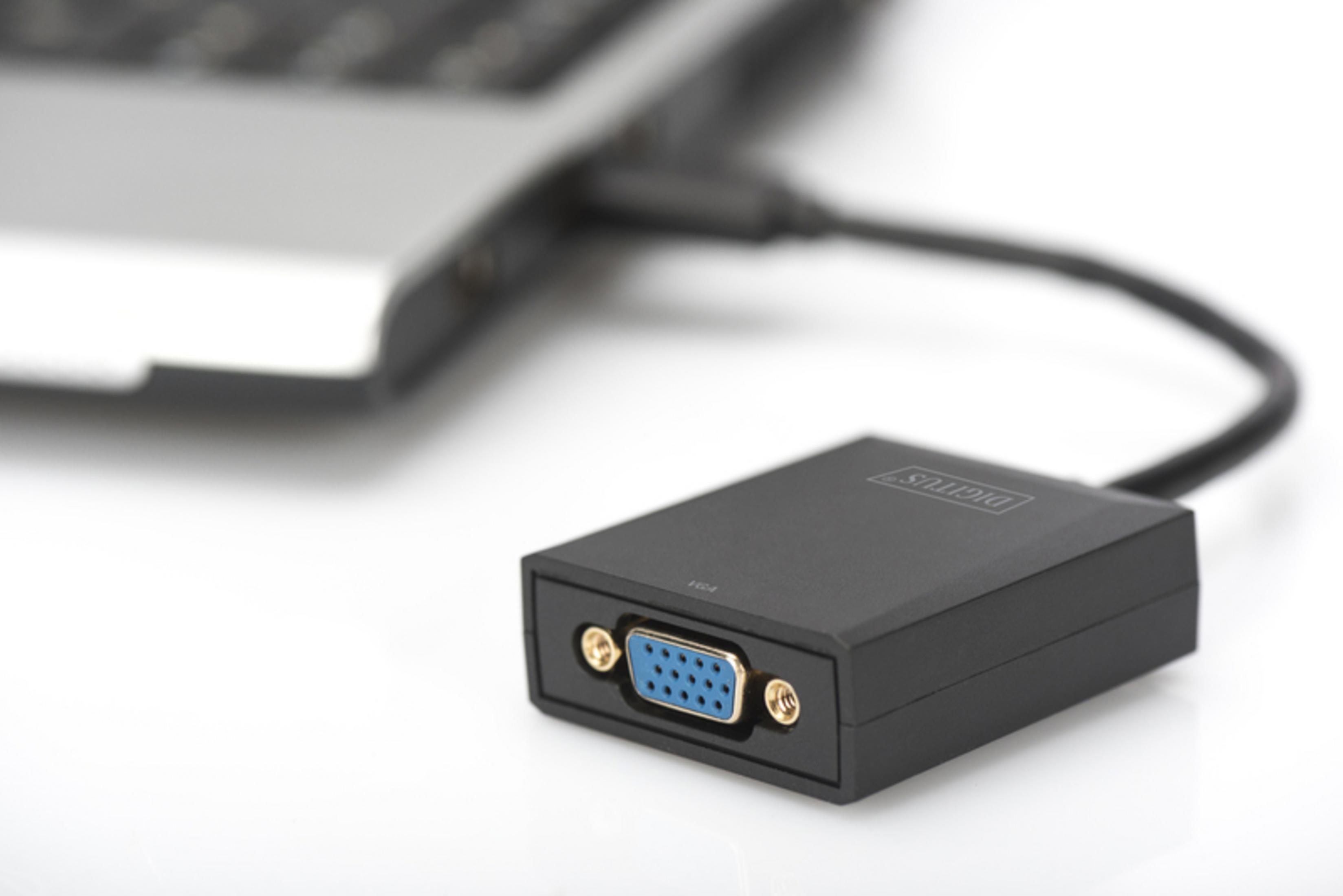 Schwarzer VGA-Adapter, der über ein schwarzes Kabel mit einem Laptop auf weißem Hintergrund verbunden ist.