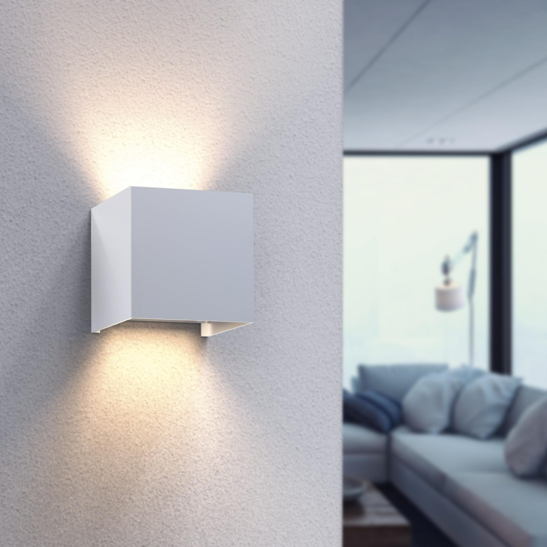 Nowoczesna biała lampa ścienna o kształcie kostki zamontowana na teksturowanej ścianie. Wnętrze rozmyte.
