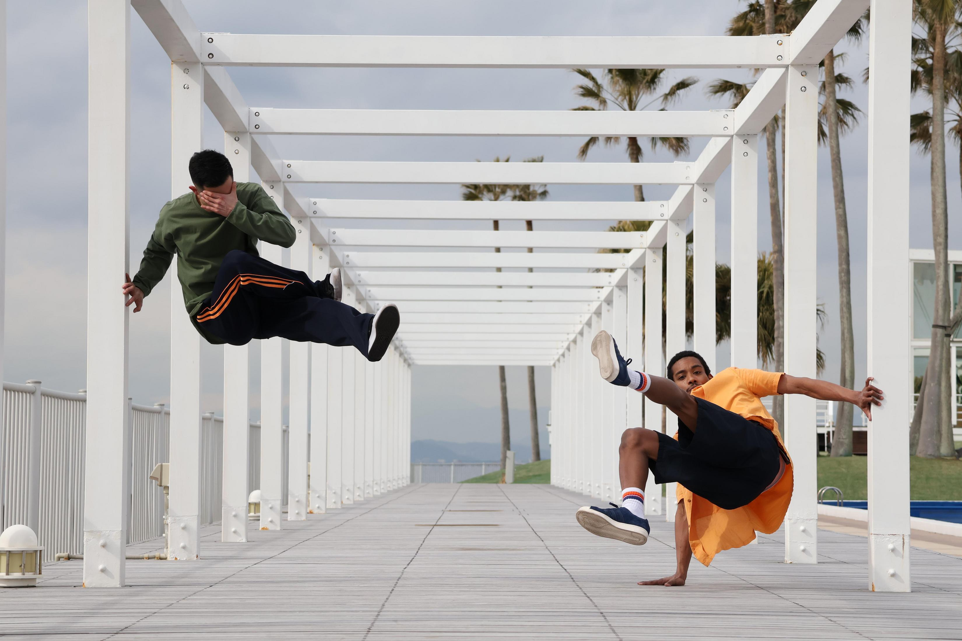 Due persone fanno breakdance su una struttura bianca. Uno è a mezz'aria, l'altro in posizione bassa.