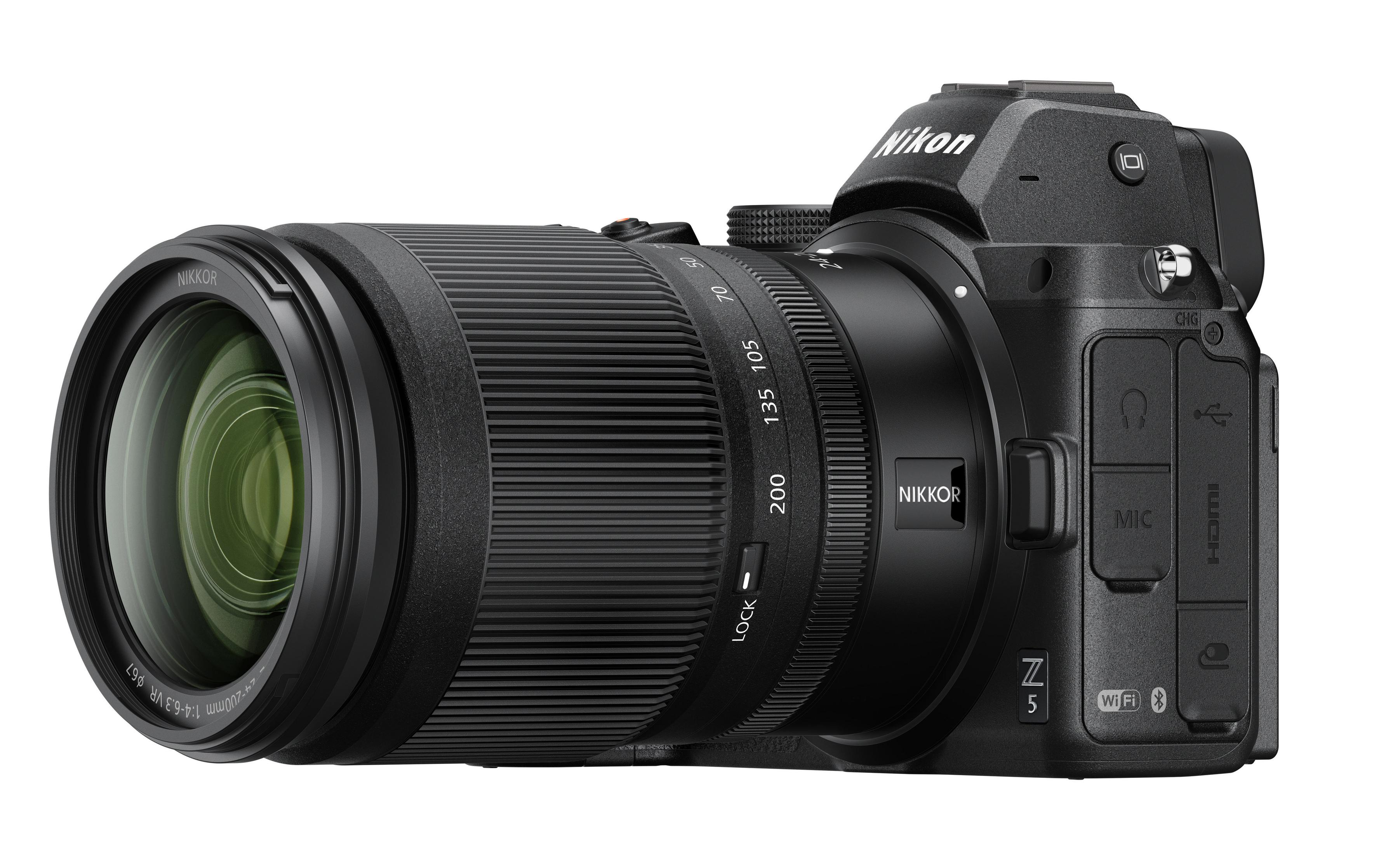Schwarze Nikon Kamera mit angesetztem Objektiv, Seitenansicht. Objektiv hat Zahlen.
