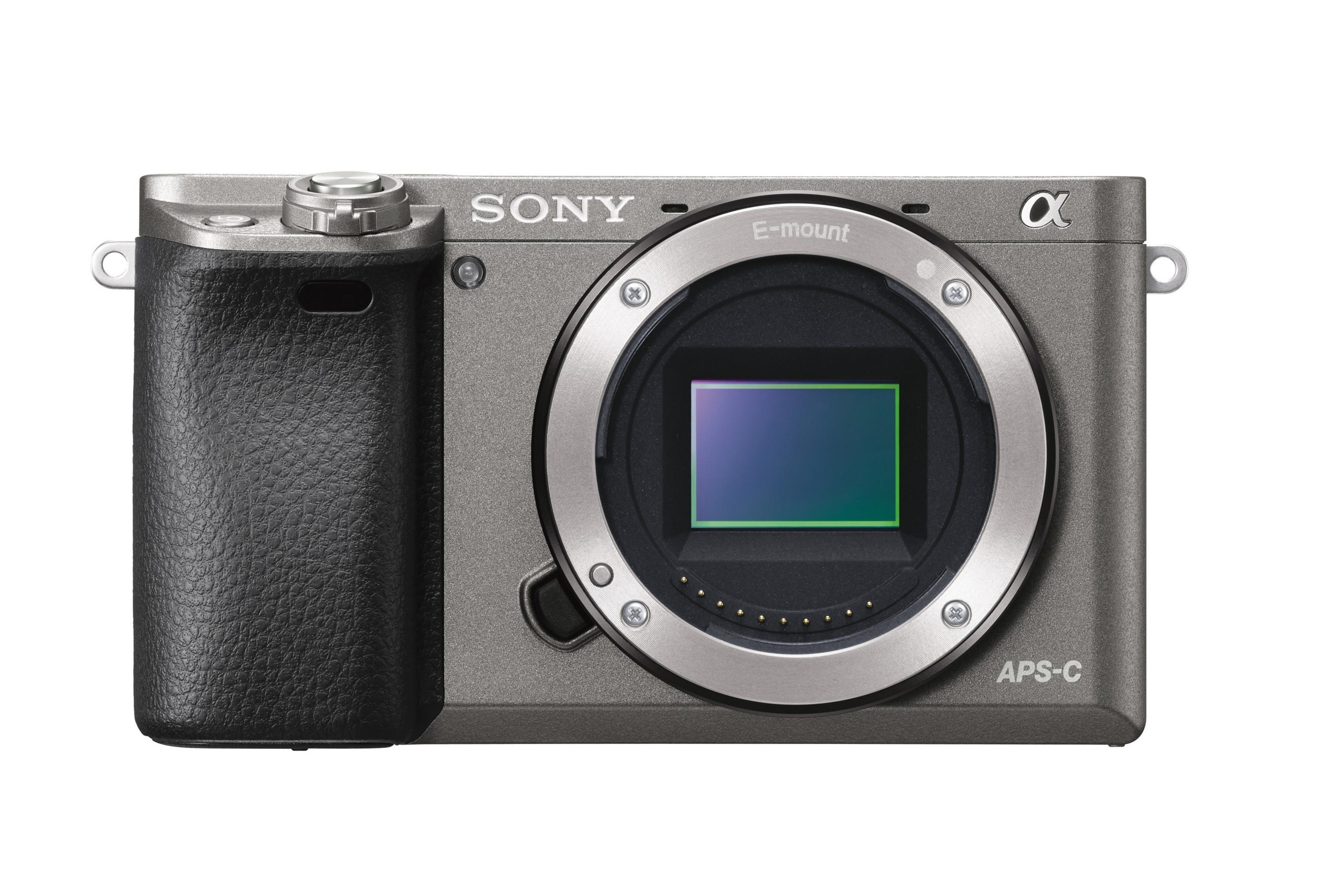 Eine graue Sony APS-C Kamera auf weißem Hintergrund, die das Objektiv zeigt.