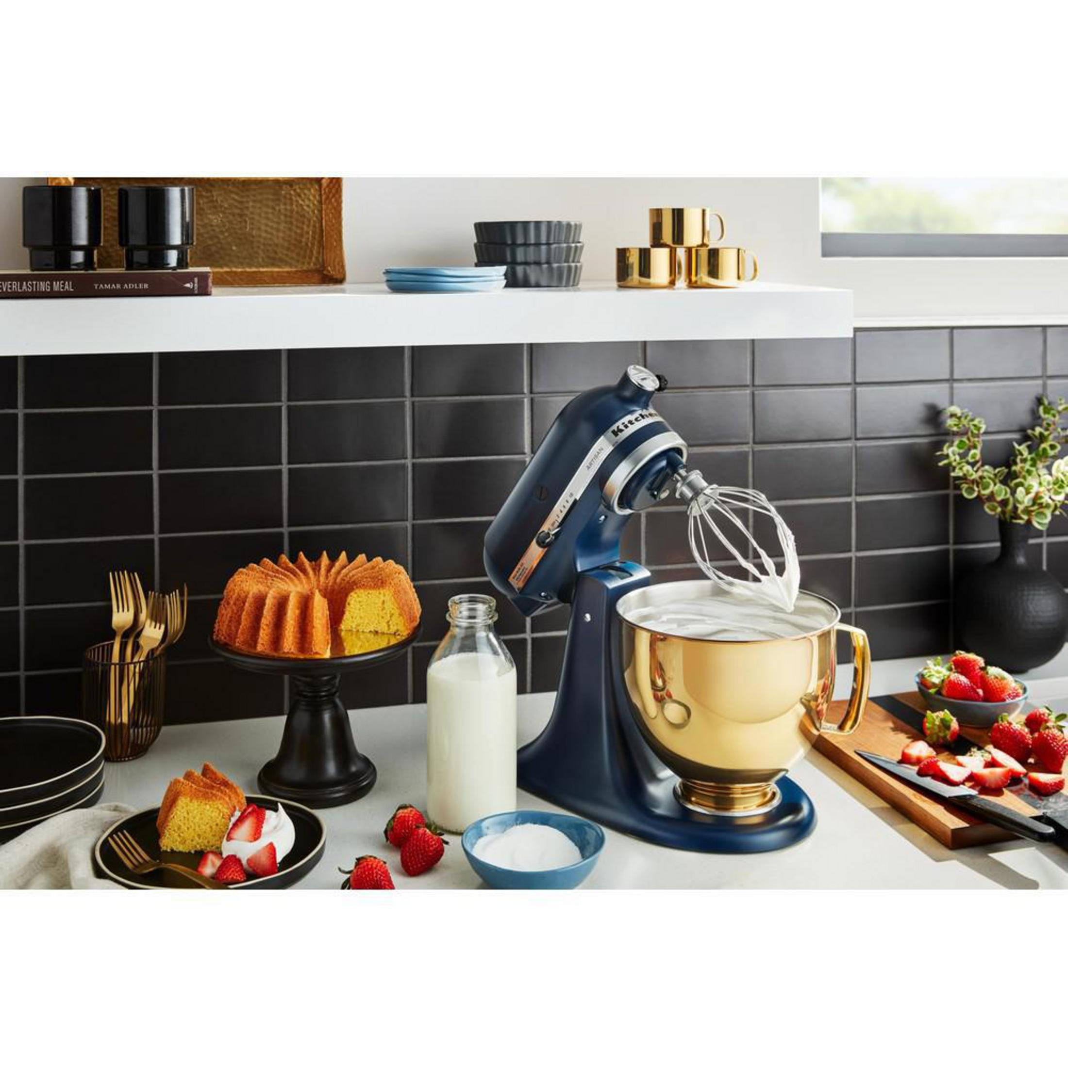 Küchenszene mit Kuchen, Mixer, Milch und Erdbeeren. Es hat einen schwarzen Fliesen Hintergrund.